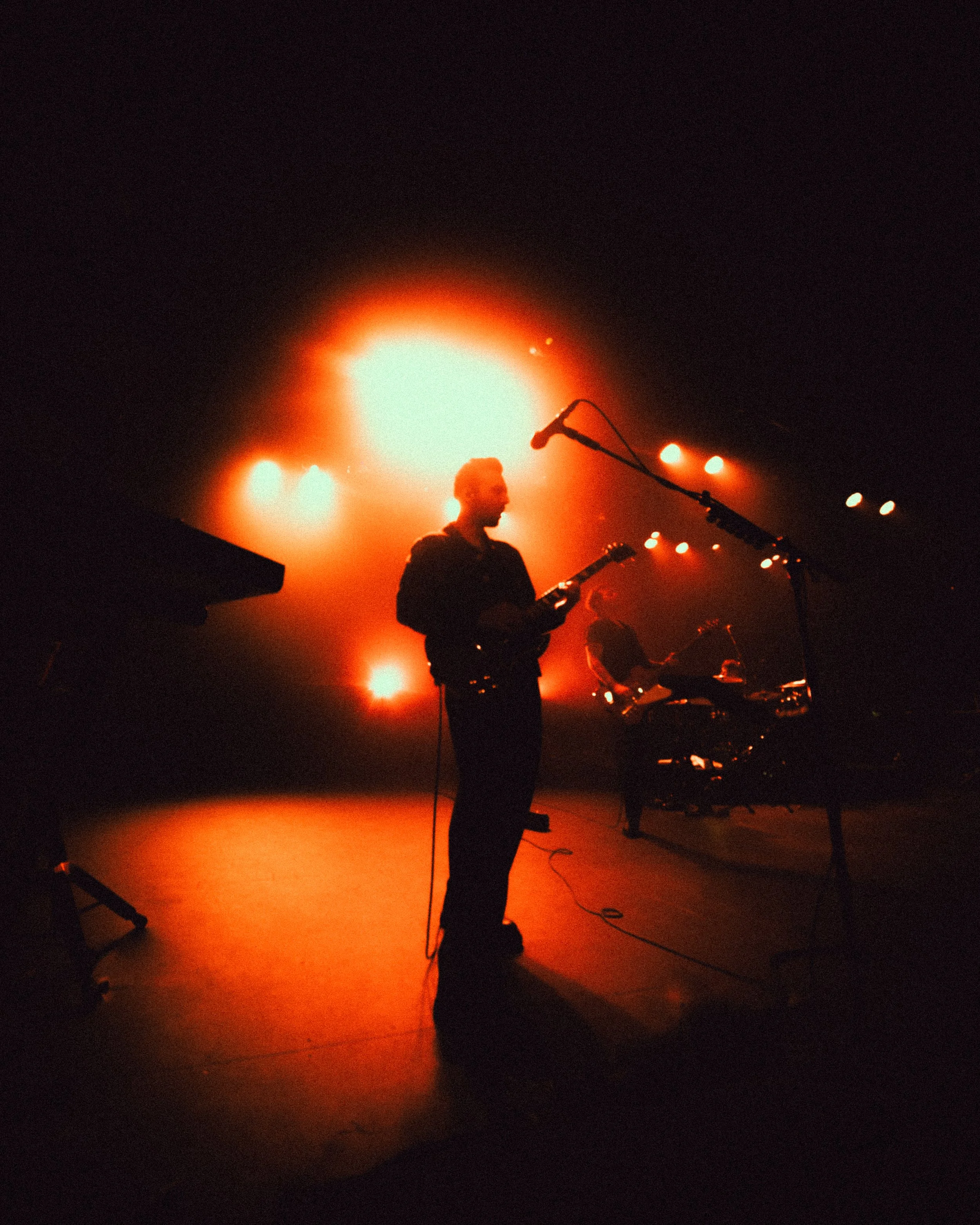 Musicians performing on stage with dramatic red lighting.