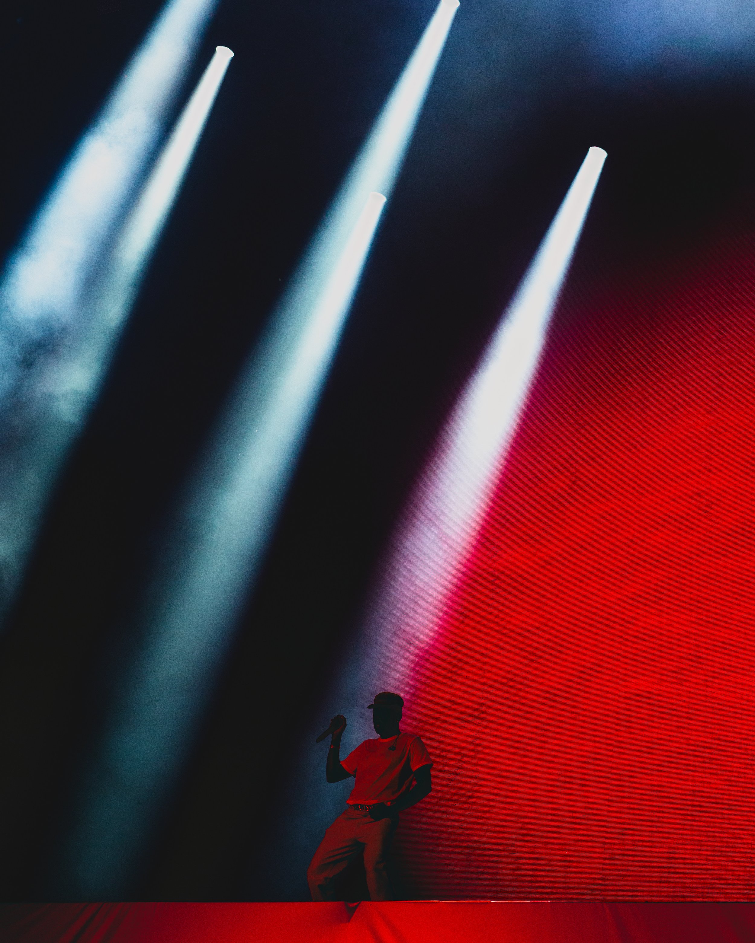 Silhouette of a person holding a microphone on stage with dramatic red and blue lighting effects.