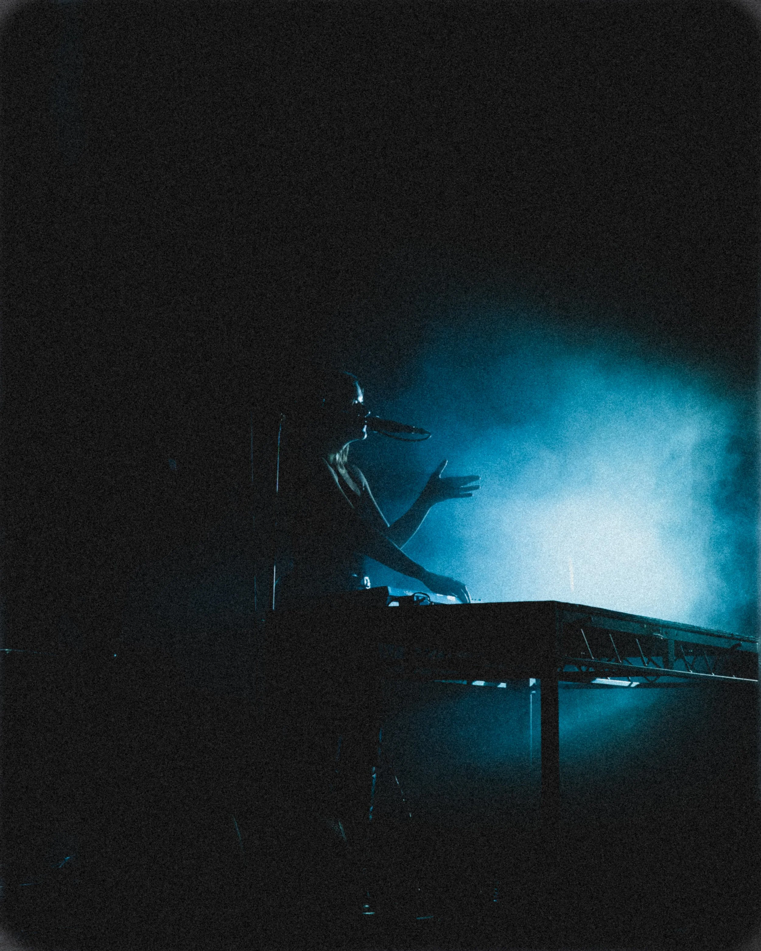 A silhouette of a woman performing on stage, with blue stage lighting creating a hazy atmosphere.