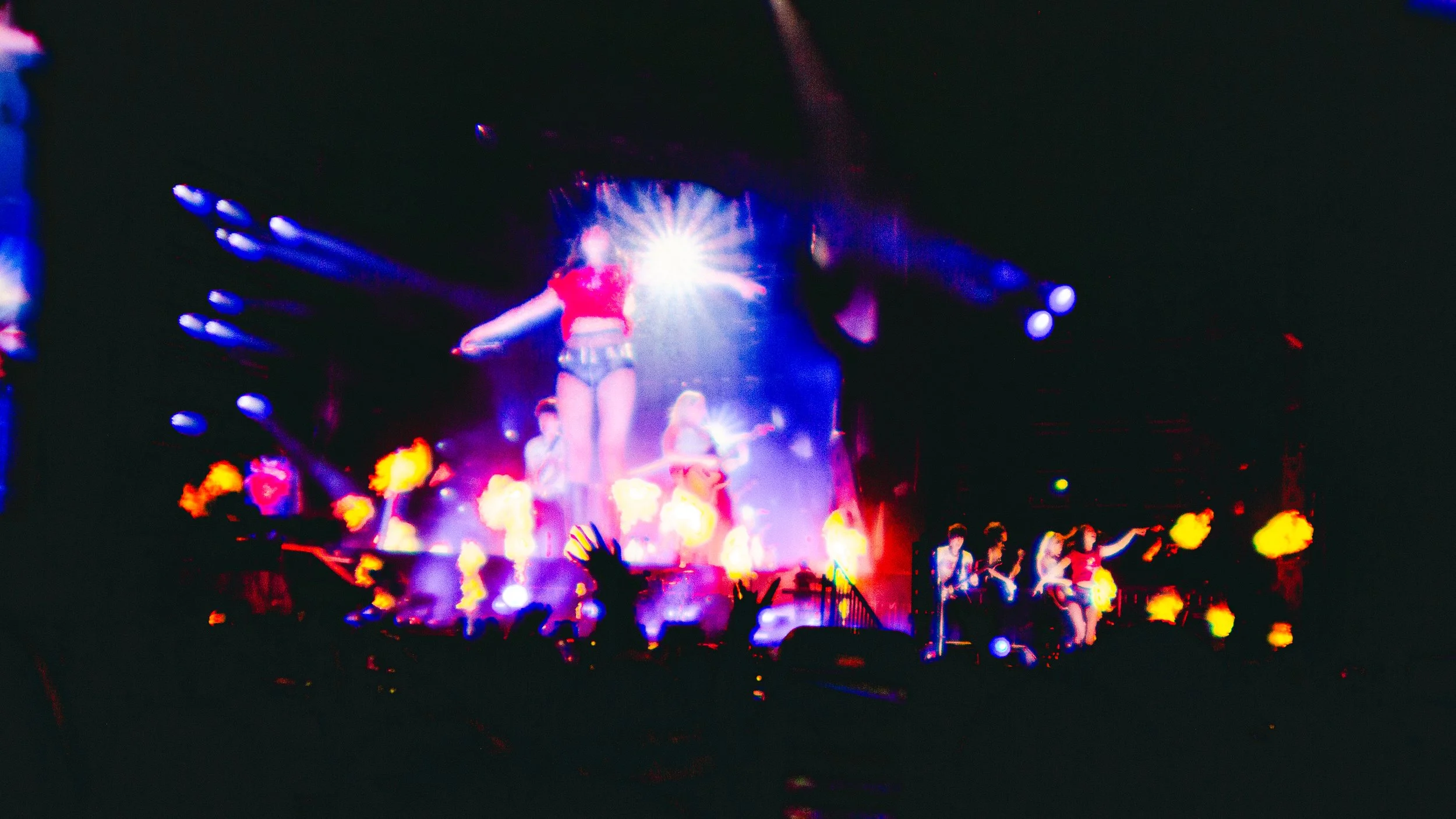 A concert stage with performers, colorful lights, and effects creating a vibrant, energetic atmosphere.
