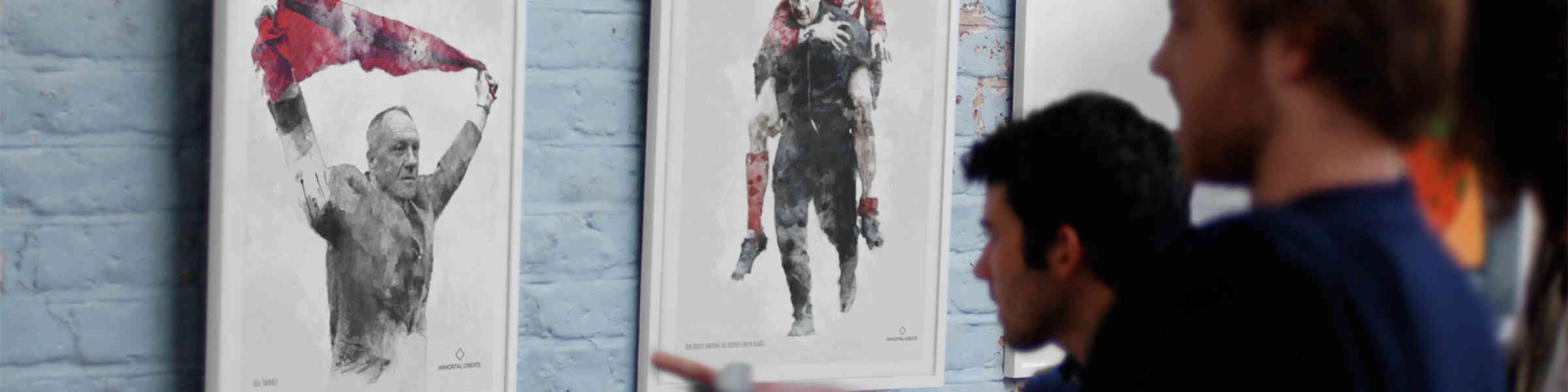 People viewing artwork sketches of athletes on a brick wall.