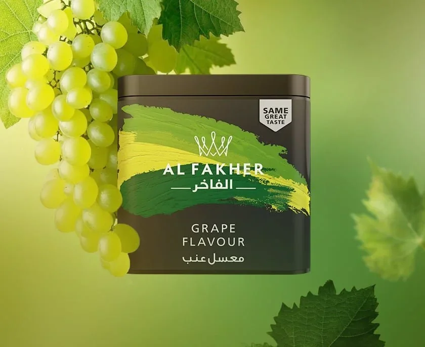A container of grape flavored shisha tobacco beside a cluster of green grapes and grape leaves on a green background.