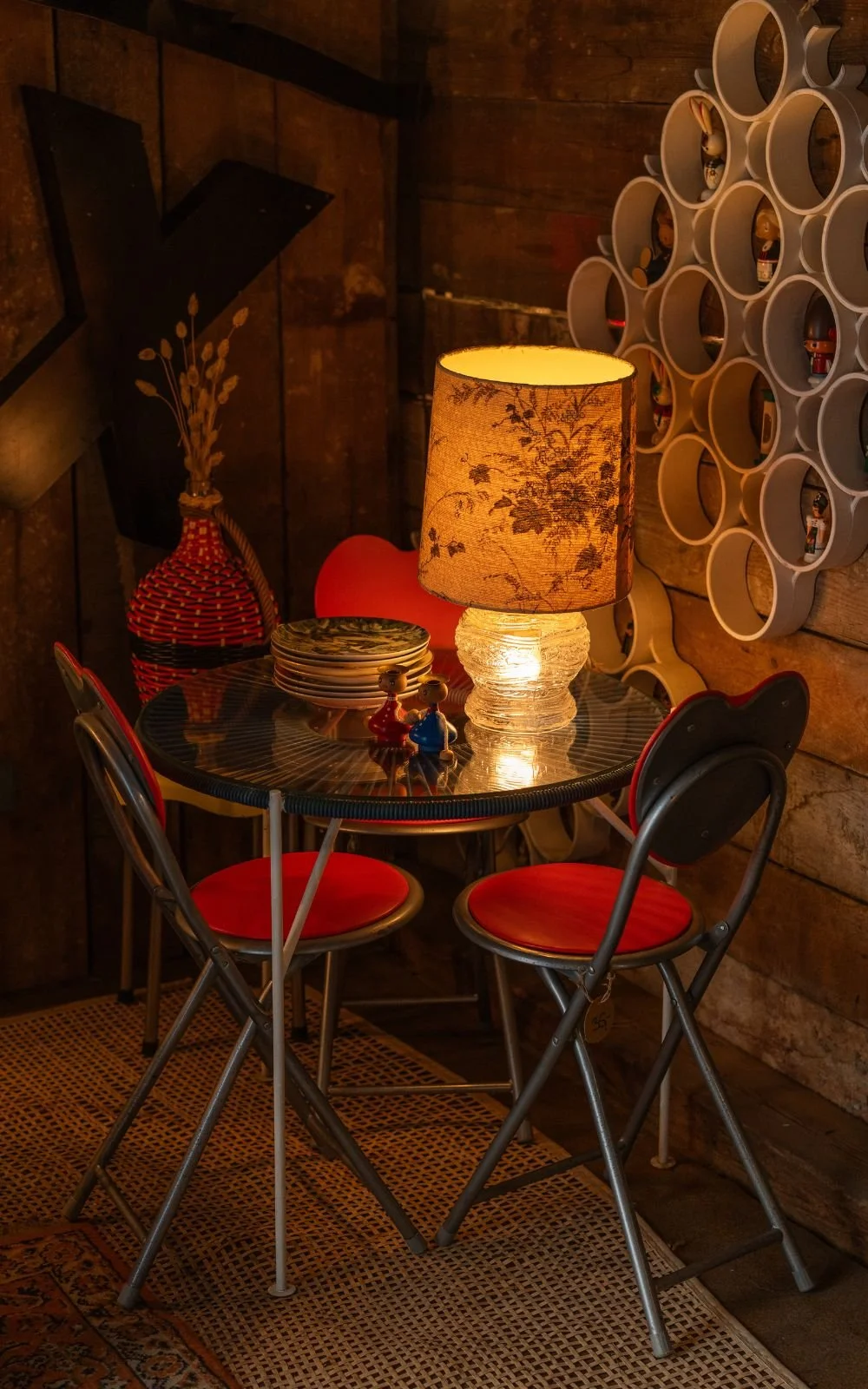 Kleiner Vintage Tisch mit Stühlen und Tischlampe in stimmungsvoller Ecke des Ladens