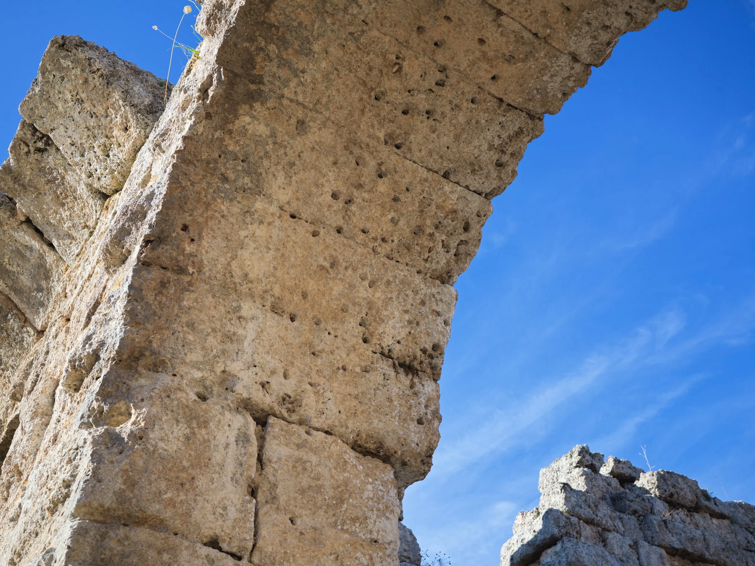 Close-up of ancient stone ruins with a bright blue sky in the background.