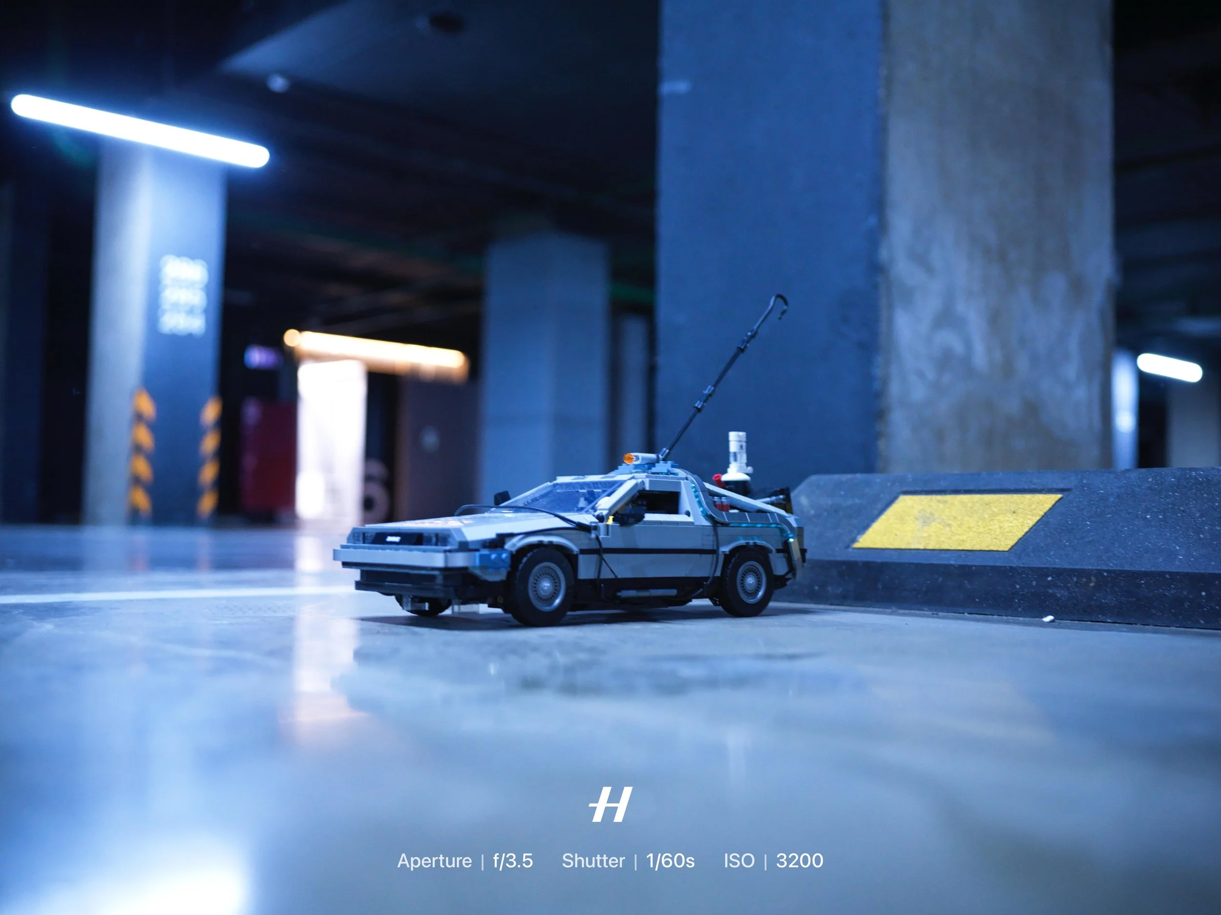 A small replica of the DeLorean time machine from the Back to the Future movies parked in a dimly lit parking garage. LEGO. Photo by Alexander Sokolyuk. Moscow, Russia