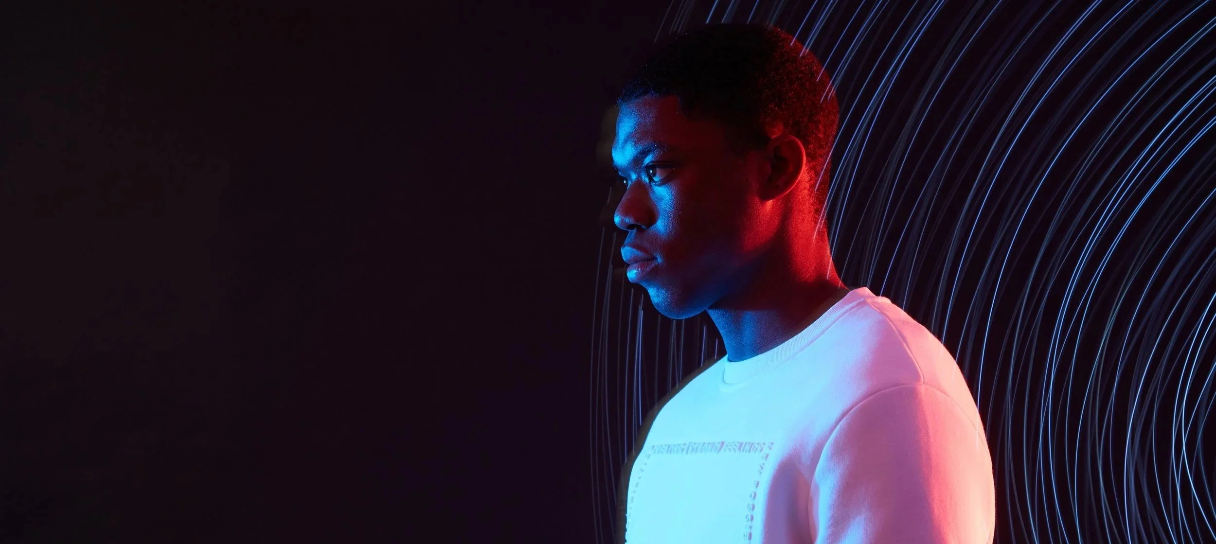 Ragazzo con tonalità di colore blu e rosso, sfondo scuro con linee light curve