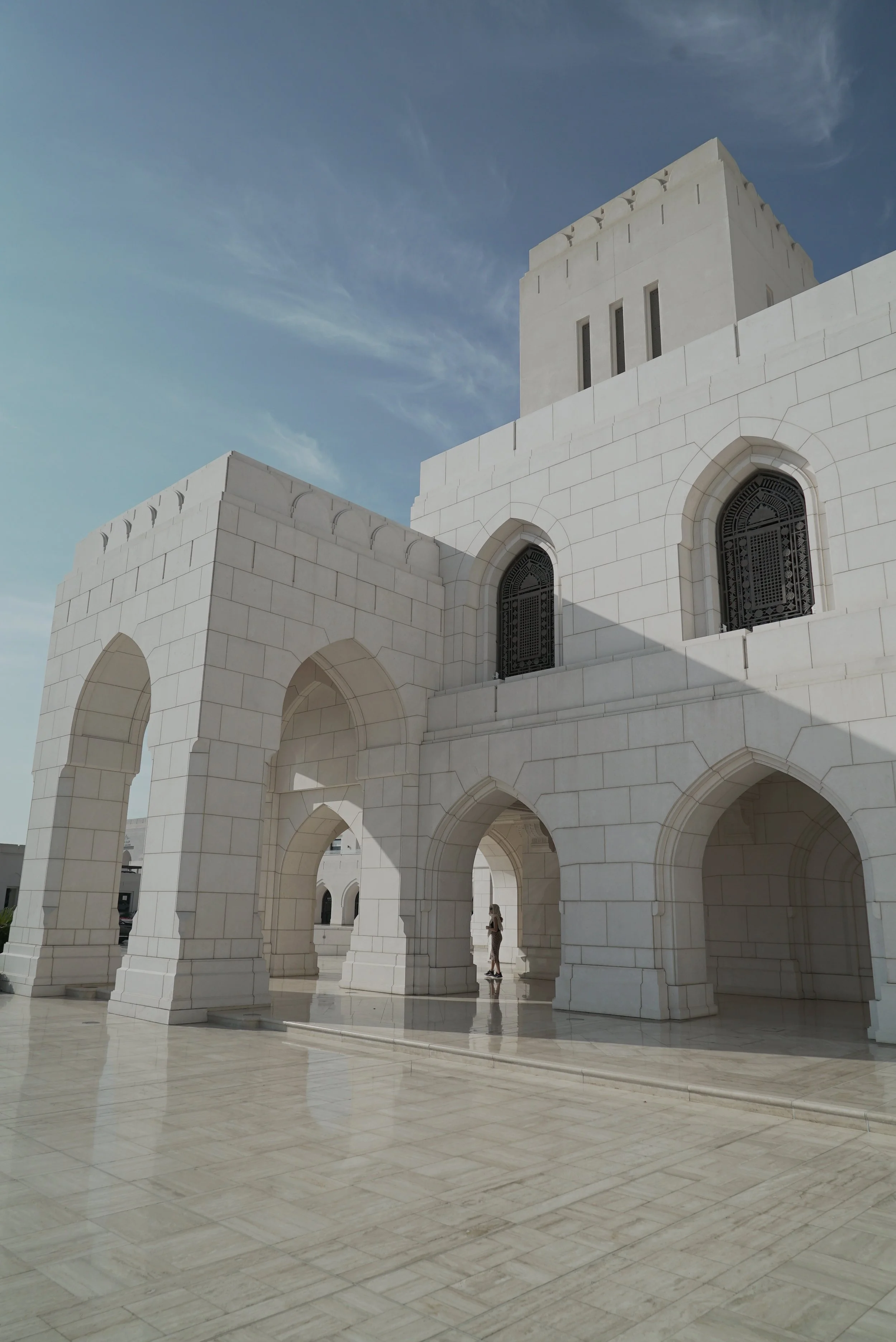 Edificio bianco con archi e finestre ricurve, sotto un cielo azzurro.