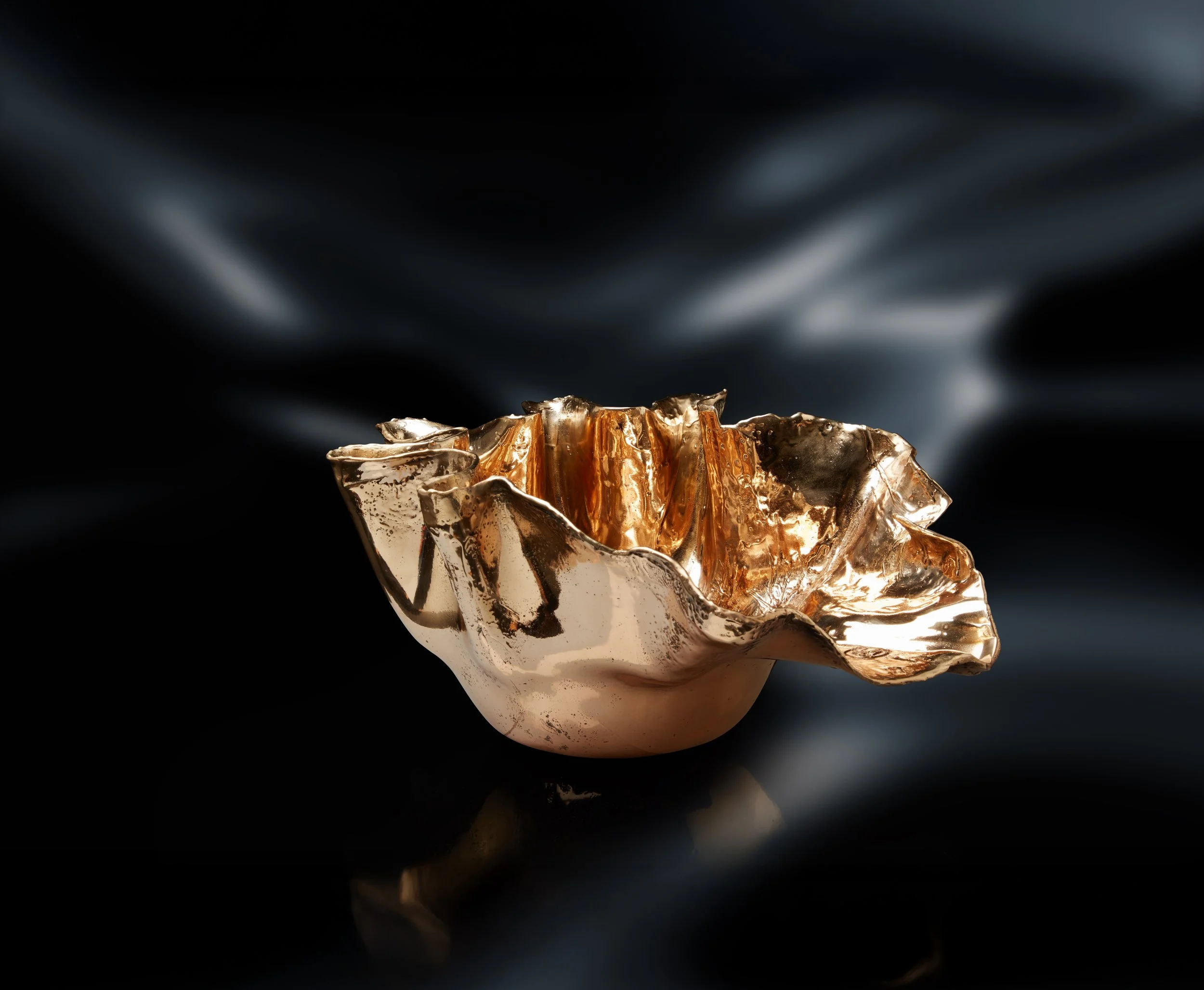 Vaso decorativo d'oro con forma organica, riflessi metallici, su sfondo scuro con luci soffuse