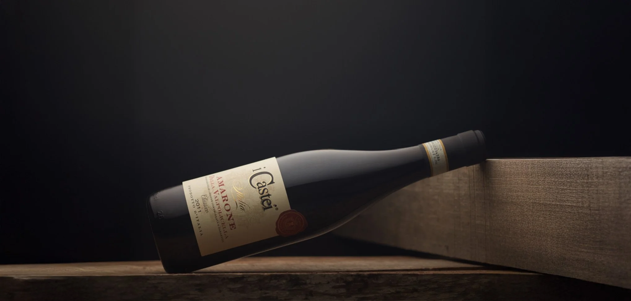 Una bottiglia di vino rosa appoggiata orizzontalmente su una superficie di legno con uno sfondo nero.