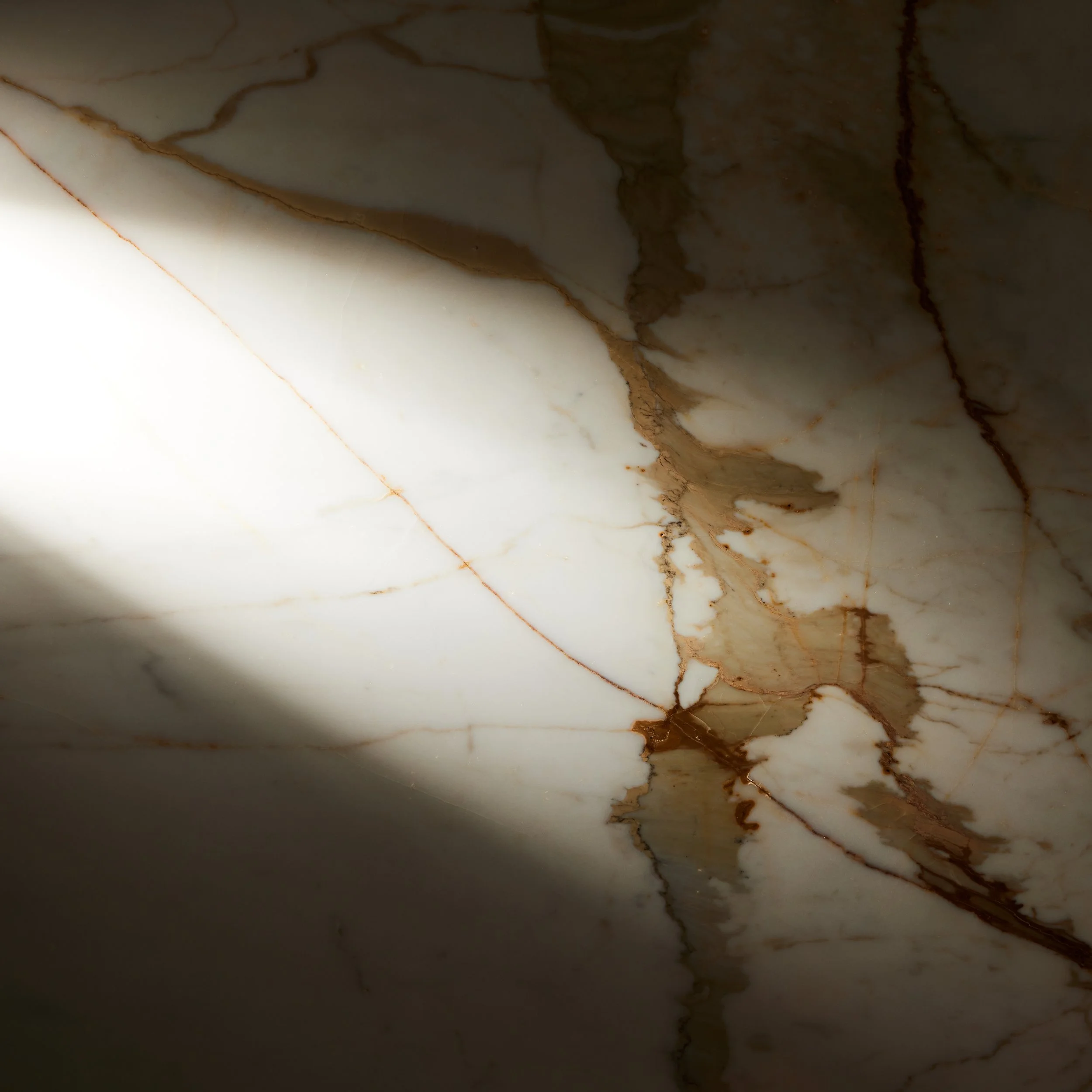 Close-up di una superficie in marmo con venature marroni e crepe.