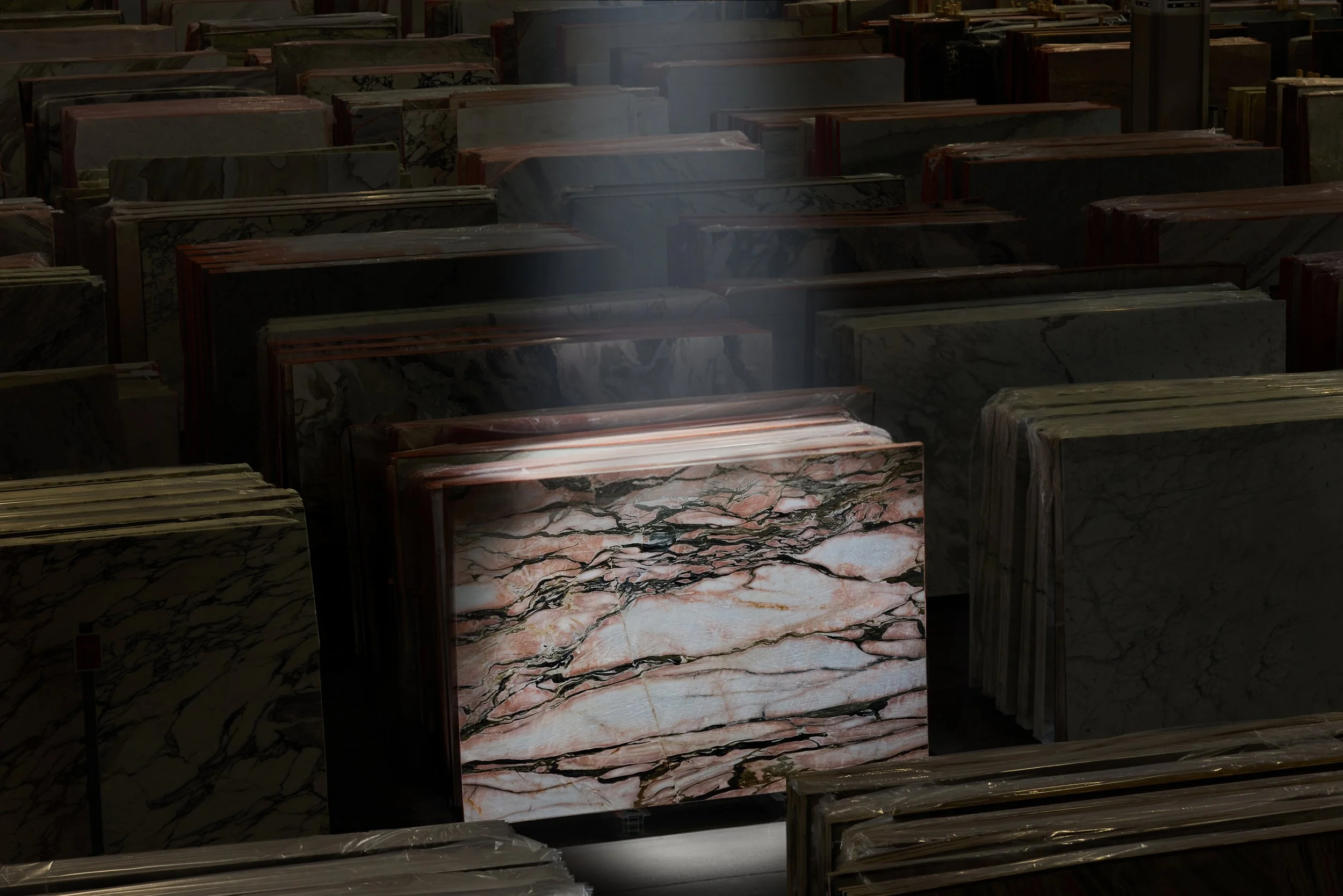 Fermacarte di marmo di vari colori e pattern, impilate in un magazzino.