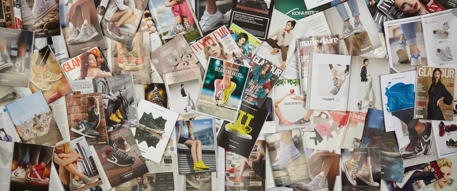 Moltissimi volantini e riviste con immagini di scarpe sportive e moda.