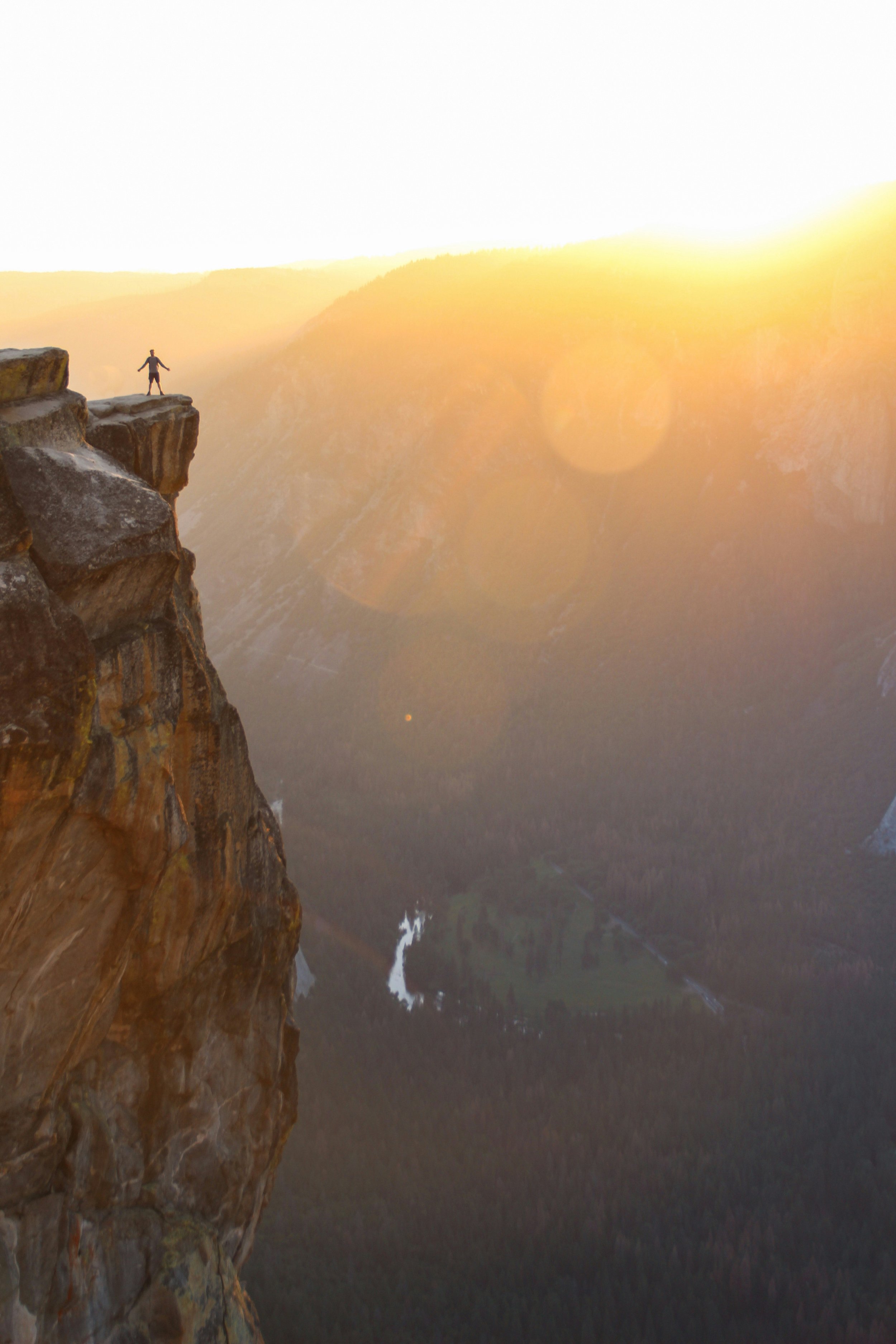 Image of a woman at the precipice of a high gorge, triumph in the sunset