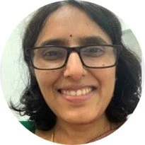 Close-up of a smiling woman with glasses and shoulder-length black hair.