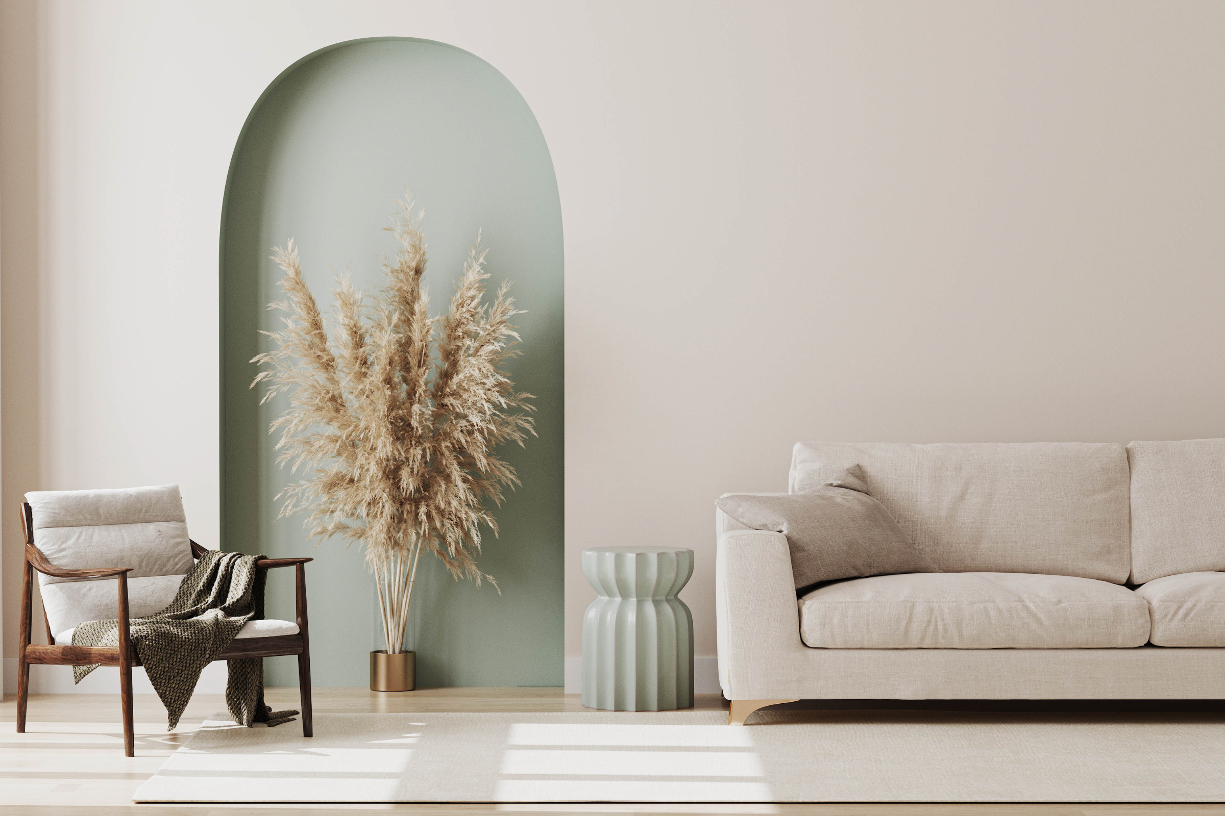 Intérieur moderne avec un fauteuil en bois et tissu beige, un vase orné de pampas, un petit tabouret vert pastel et un canapé beige dans un salon lumineux