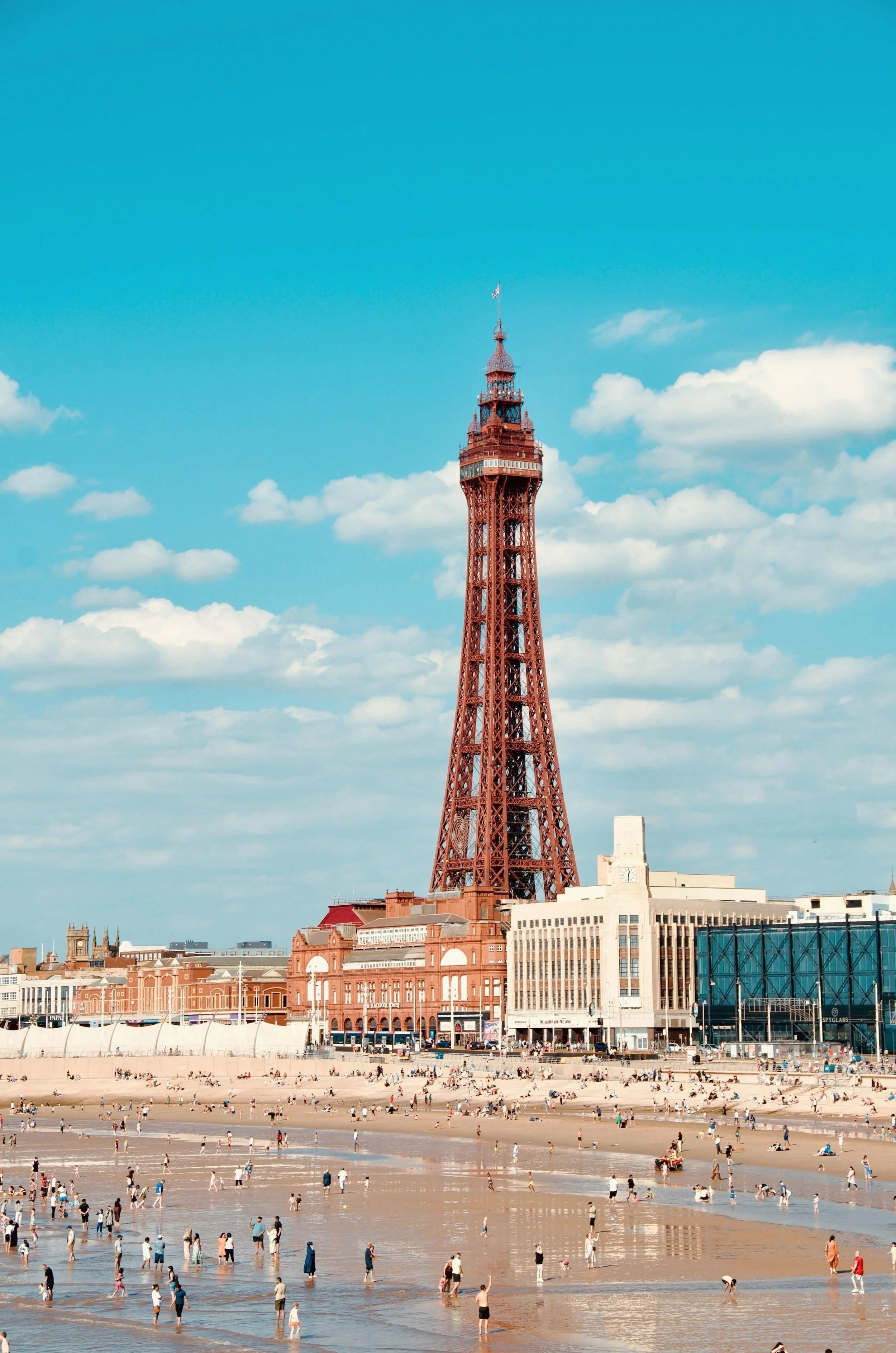 Blackpool Tower on a sunny day with a crowded beach in the foreground.