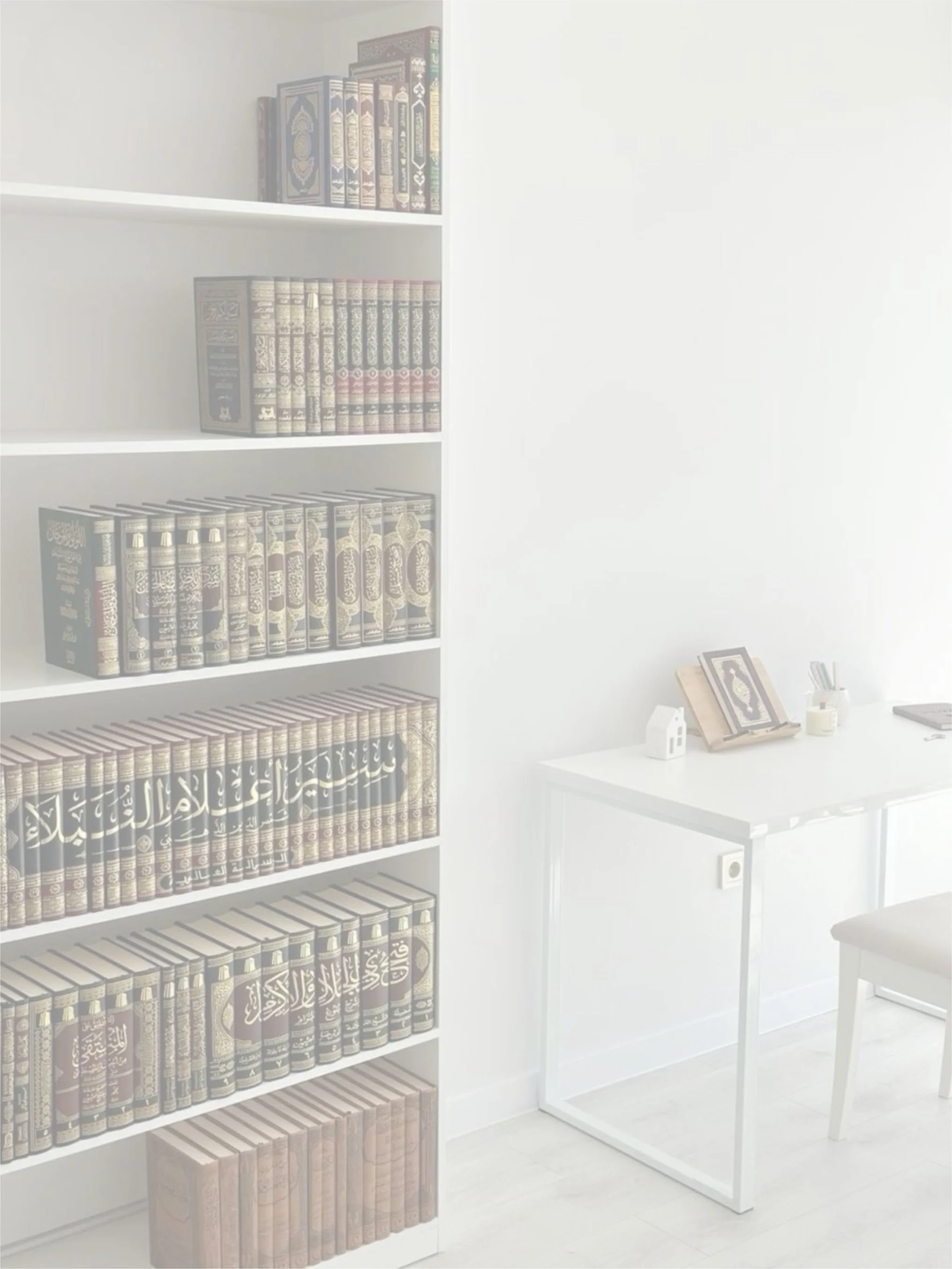 White bookshelf filled with Arabic and encyclopedic books next to a white desk with a framed picture, notebook, and writing utensils in a bright, minimalistic room.