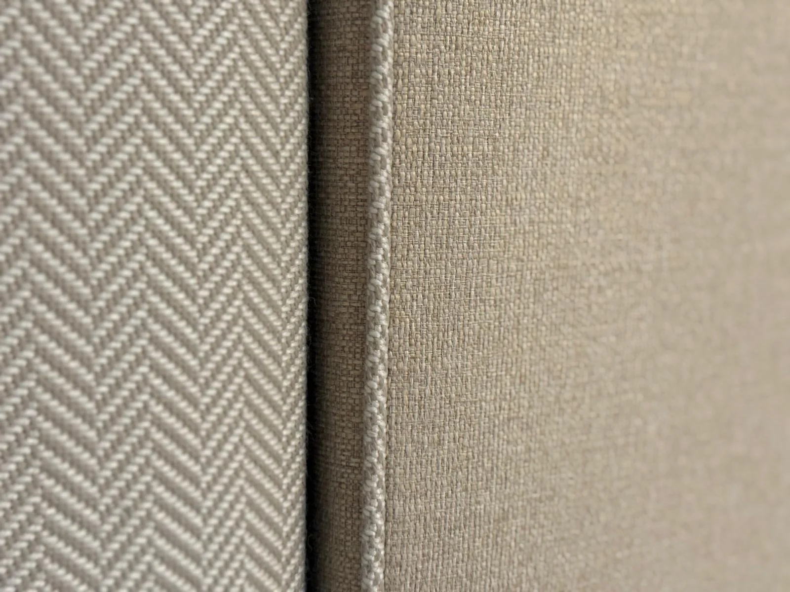 Close-up of beige fabric cushions with different textures, one with a woven pattern and the other with a plain surface.