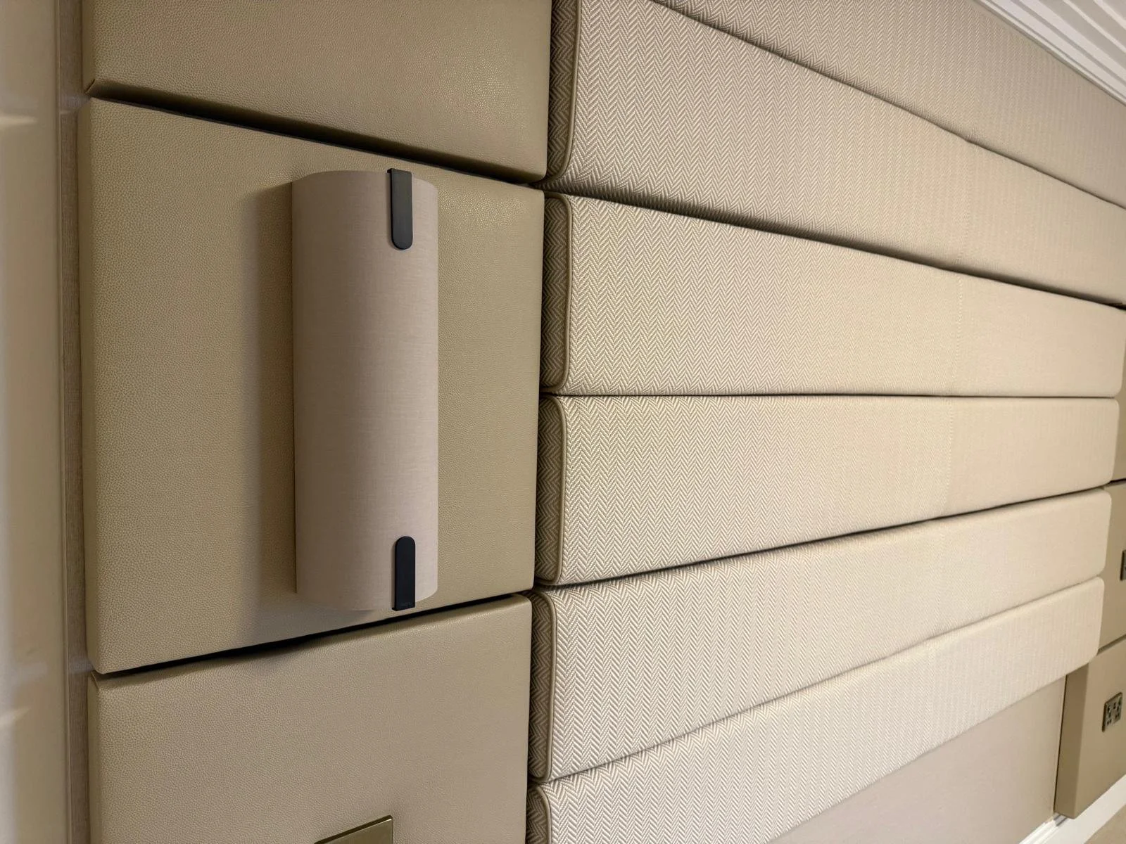 A row of padded beige headboards and an adjustable beige reading light attached to the wall behind them.
