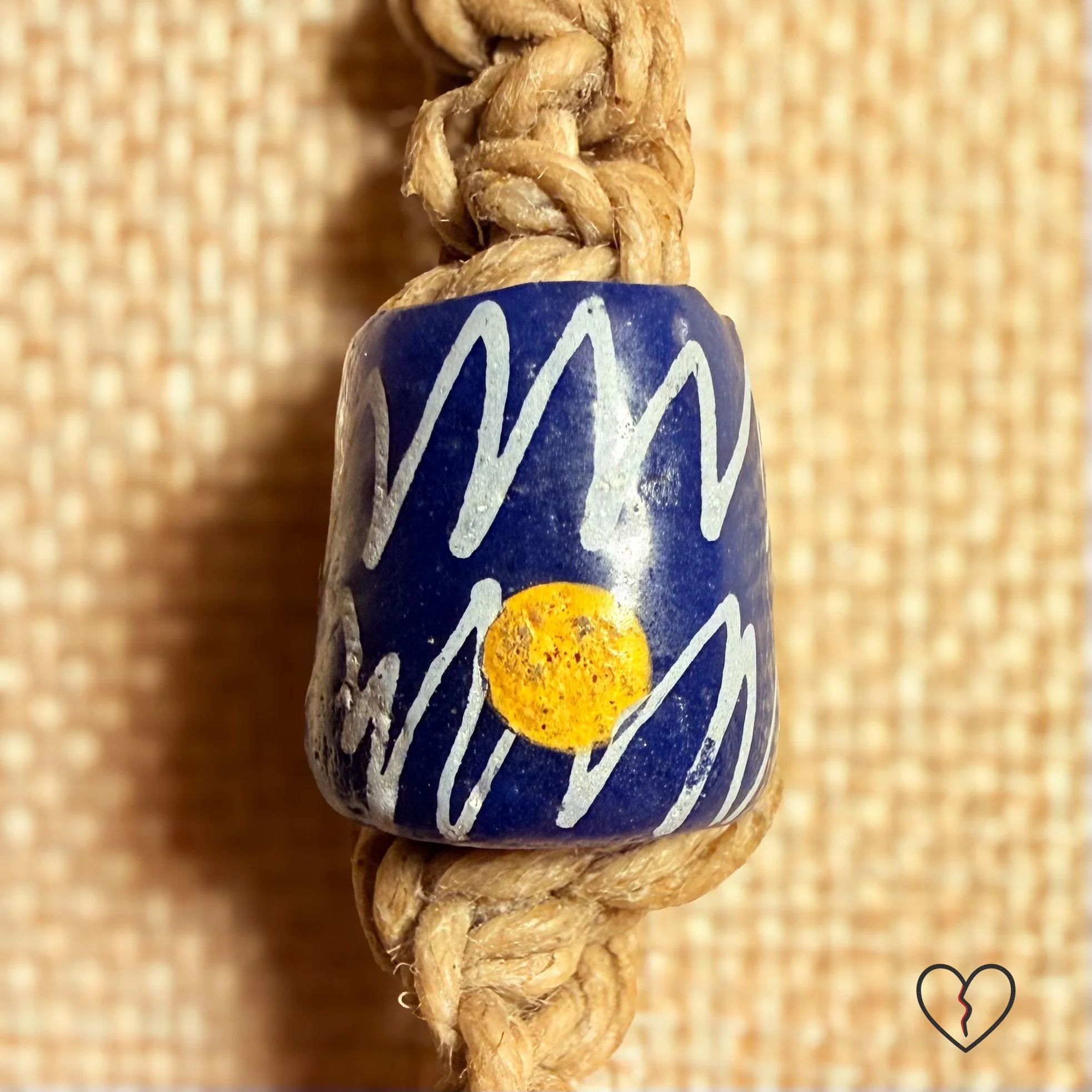 Fiber necklace with yellow trade bead, wool circle, hemp cord, and tassel.