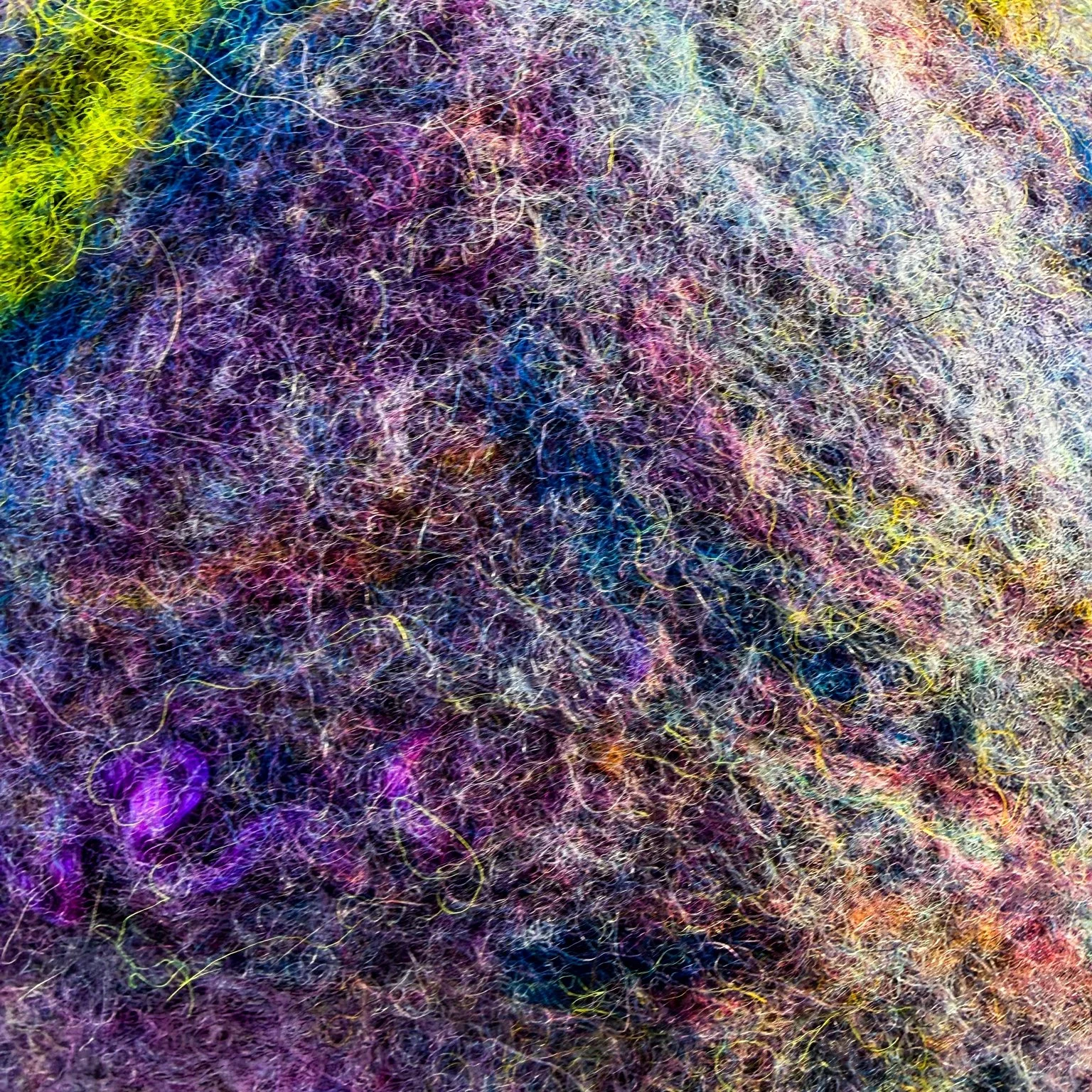 Detailed macro view of layered felted wool fibers showing color variation and natural fiber movement.