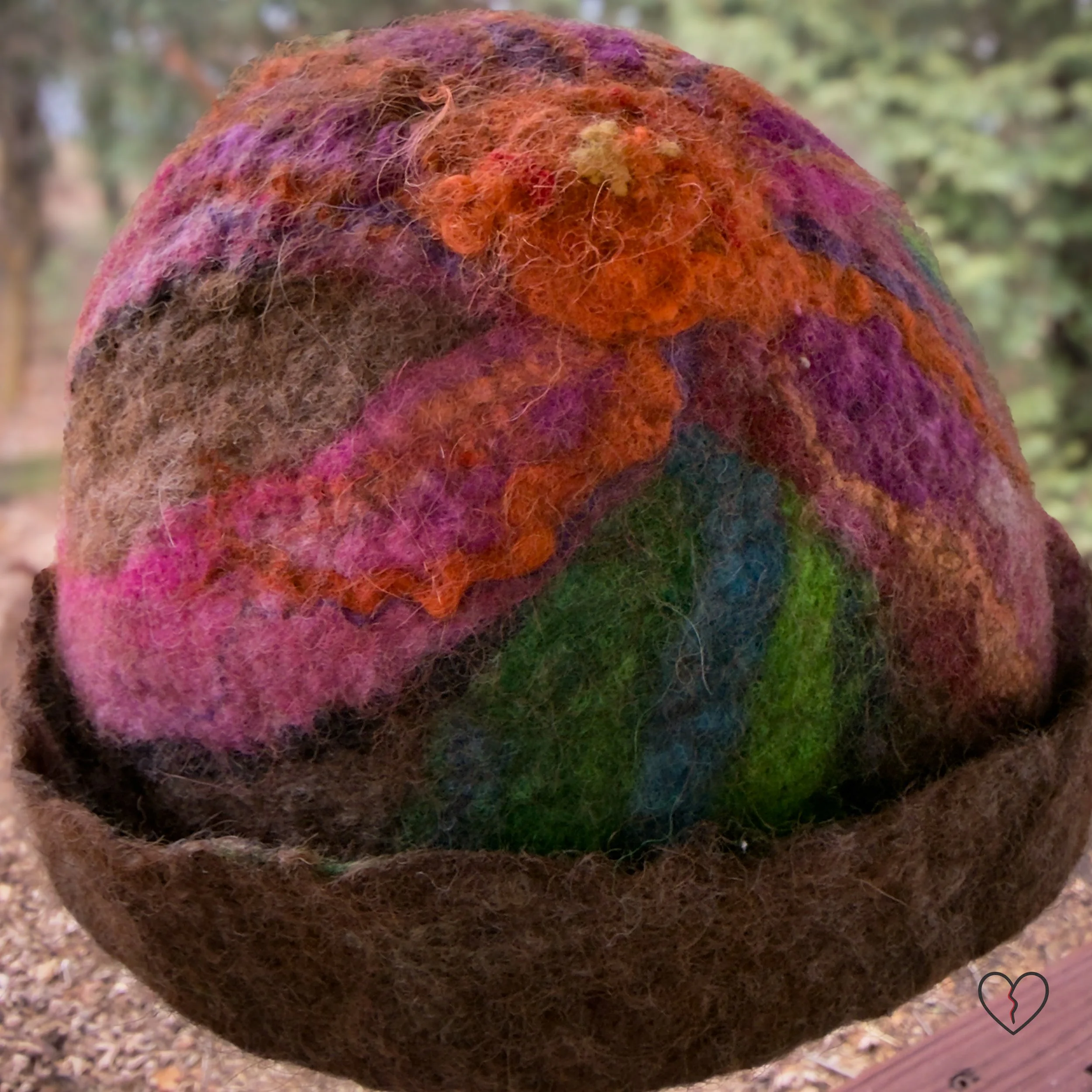 Top view of felted hat showing pink and orange flower made from wool locks and silk