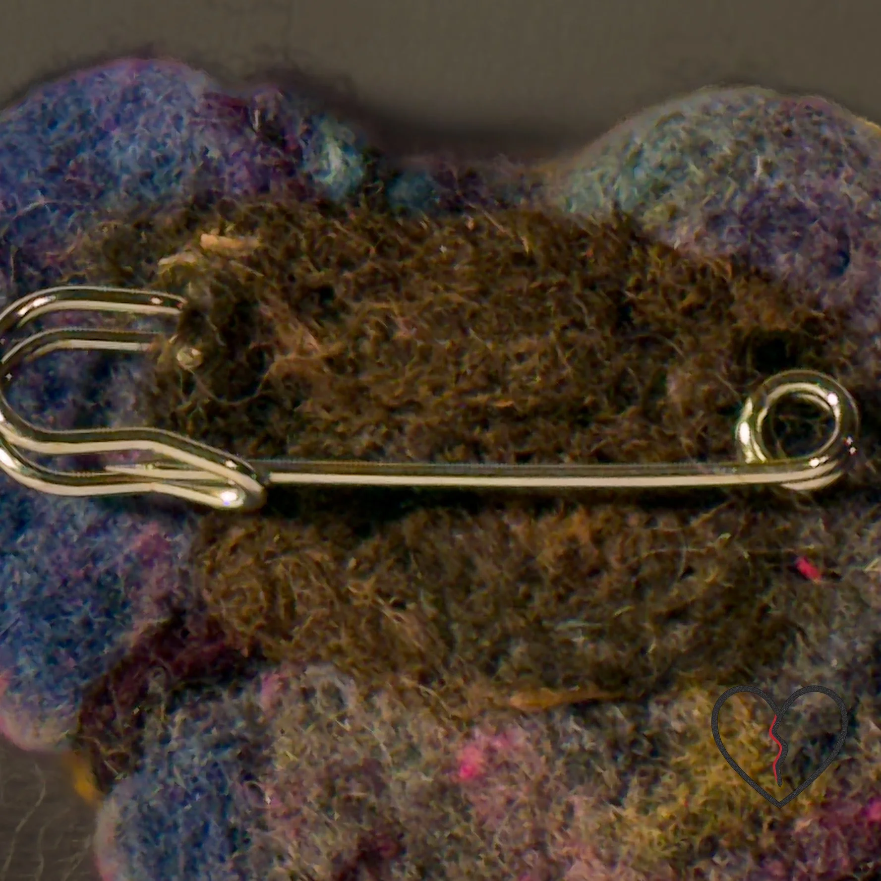 Back of hand-felted wool art pin showing 2.5-inch metal pin backing designed for heavy fabrics.