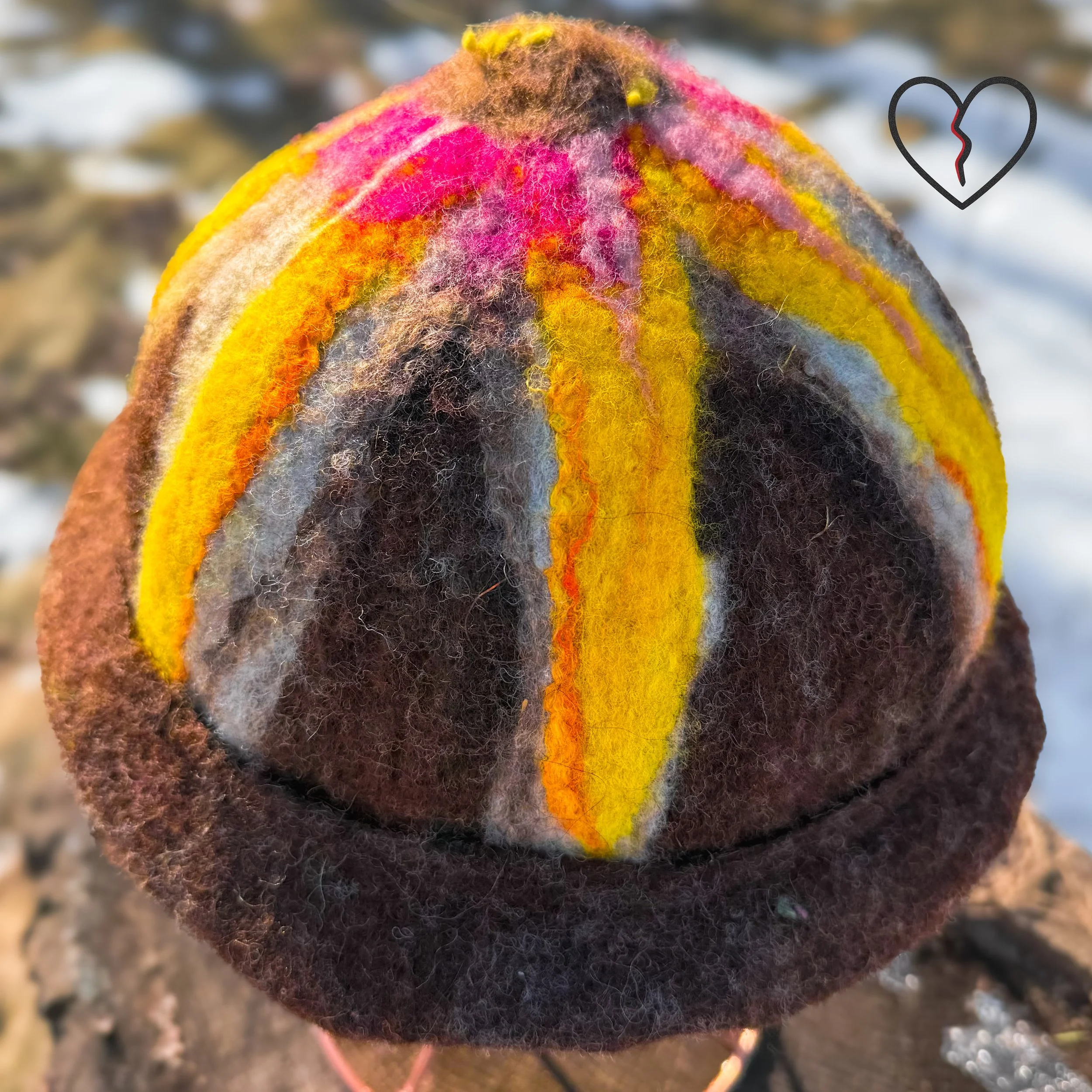 Overhead detail of flower crown on felted wool hat showing petal-like fiber layout and organic texture.