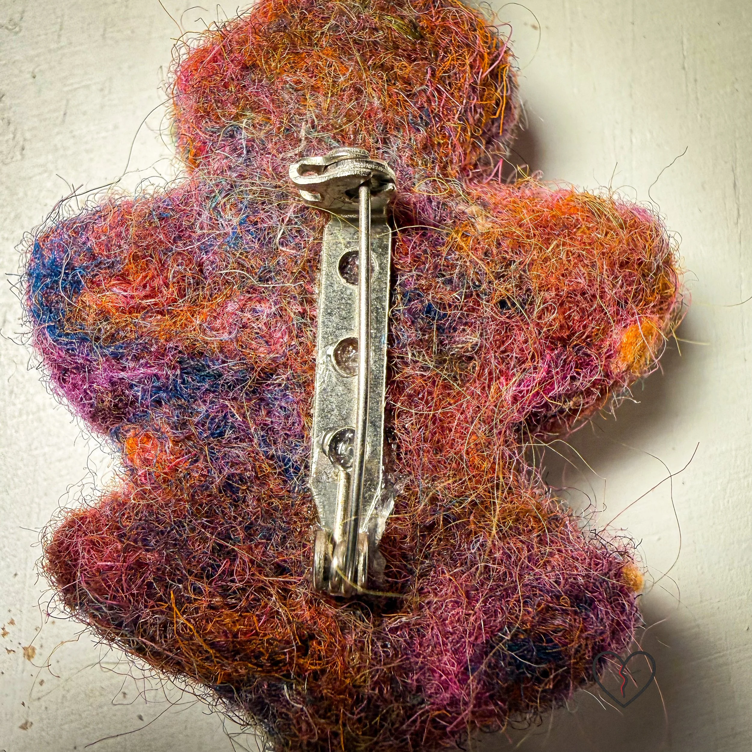 A group of handmade needle felted wool art pins, each one of a kind, showing organic shapes, soft sculptural texture, and layered wool fibers in muted seasonal tones.