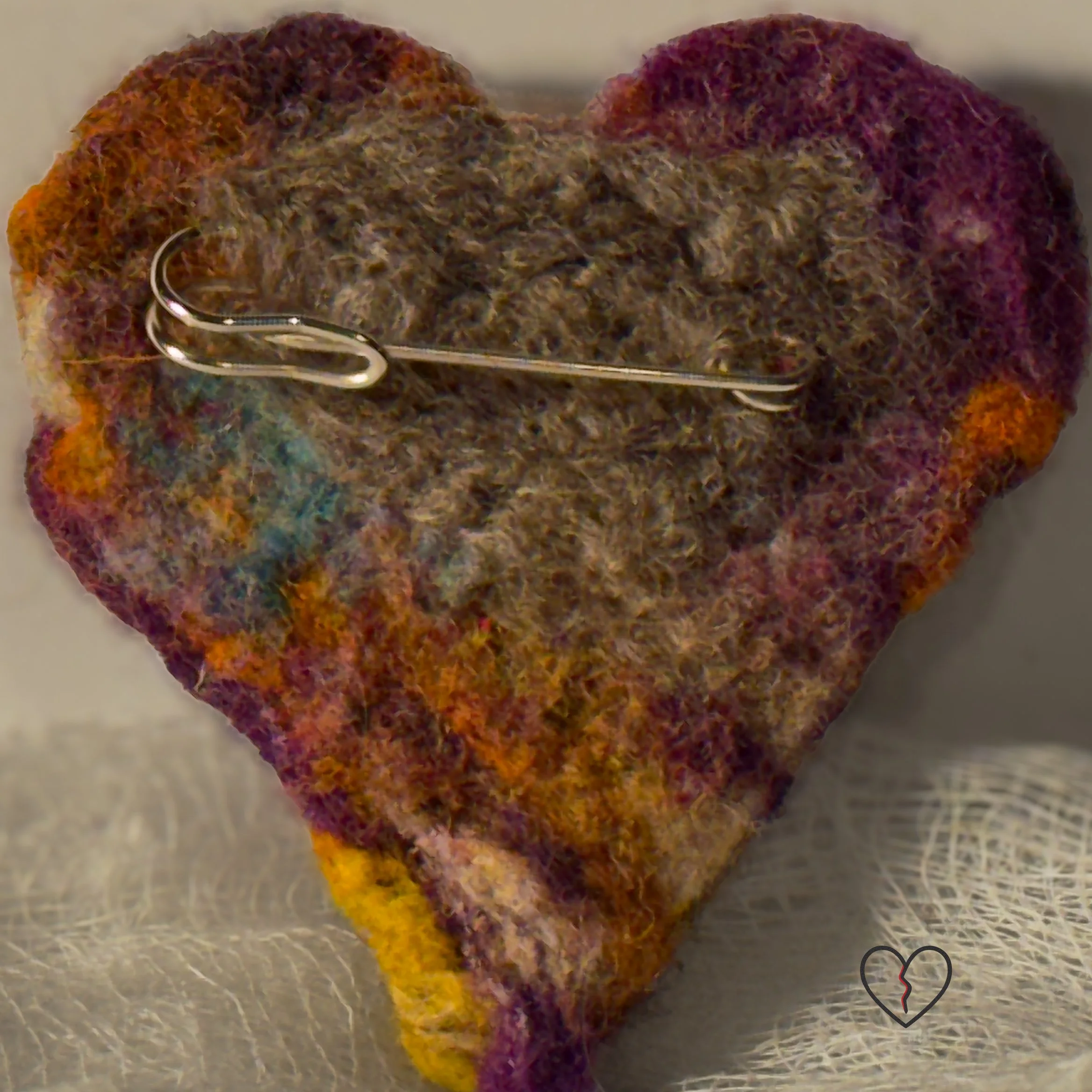 Needle-felted wool art pin broken heart with layered multicolored fibers and a stone-like texture, part of the Broken Heart series.