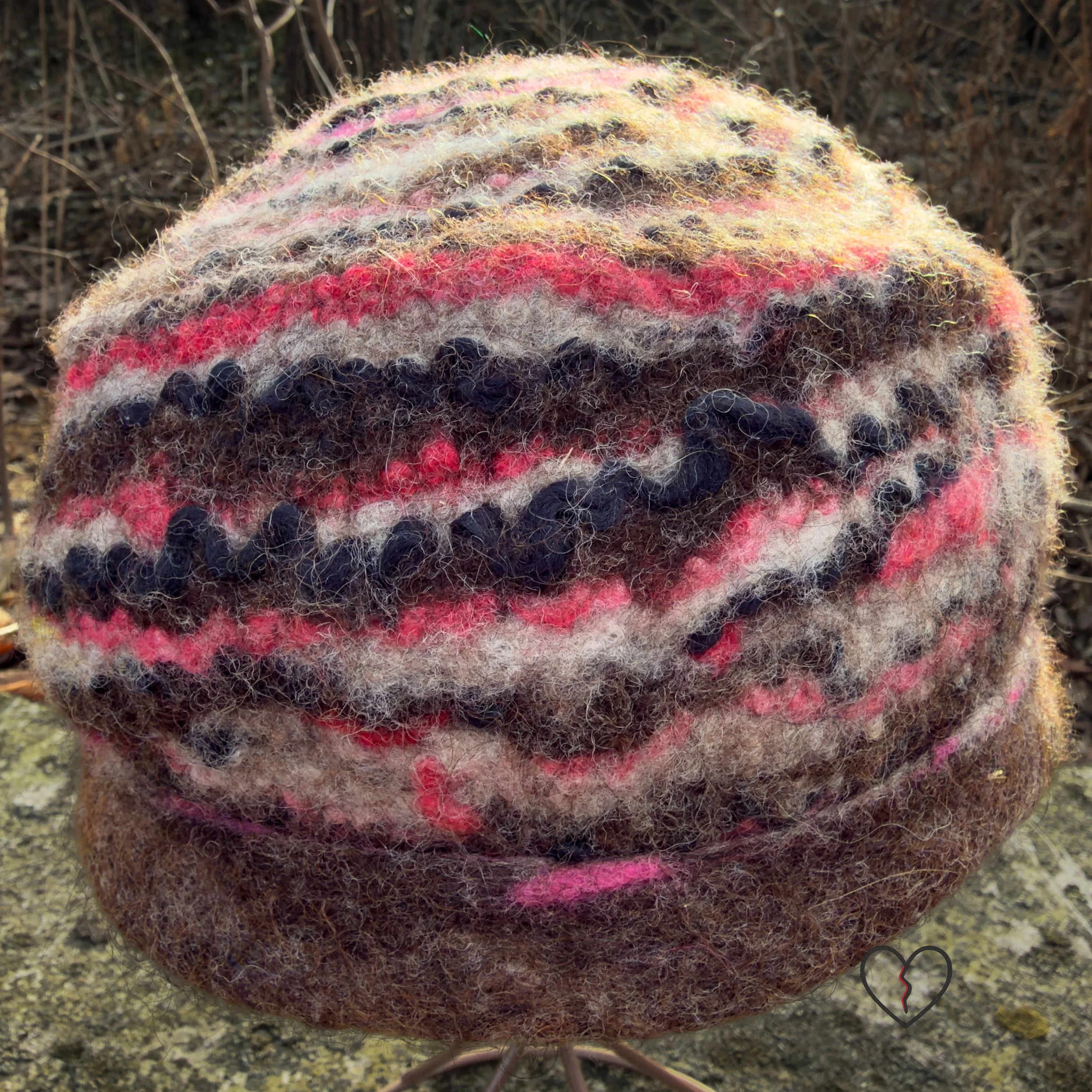 Straight-on back view of a one-of-a-kind felted wool hat with organic rippling stripes and a soft architectural silhouette.