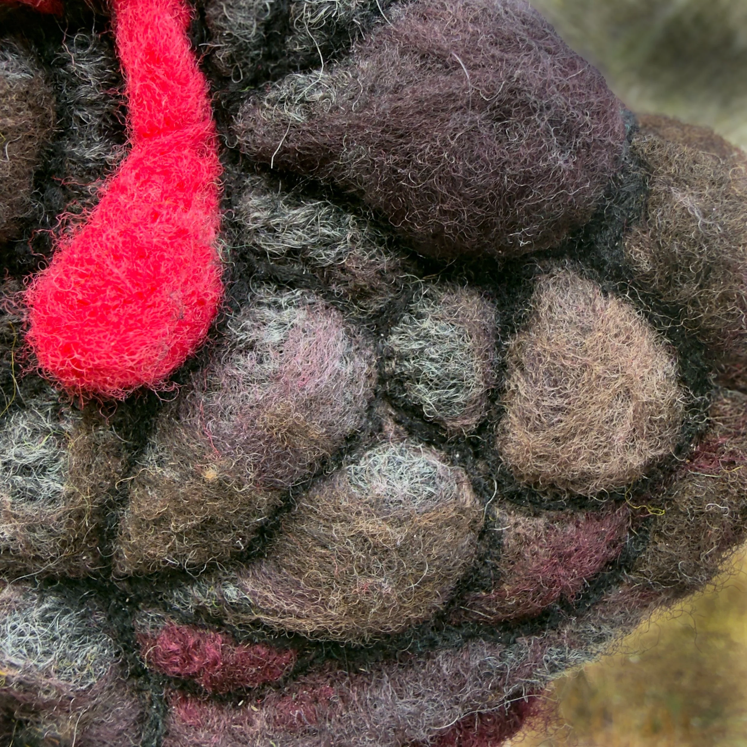 Macro view of felted wool stone texture with layered fibers and sculptural depth