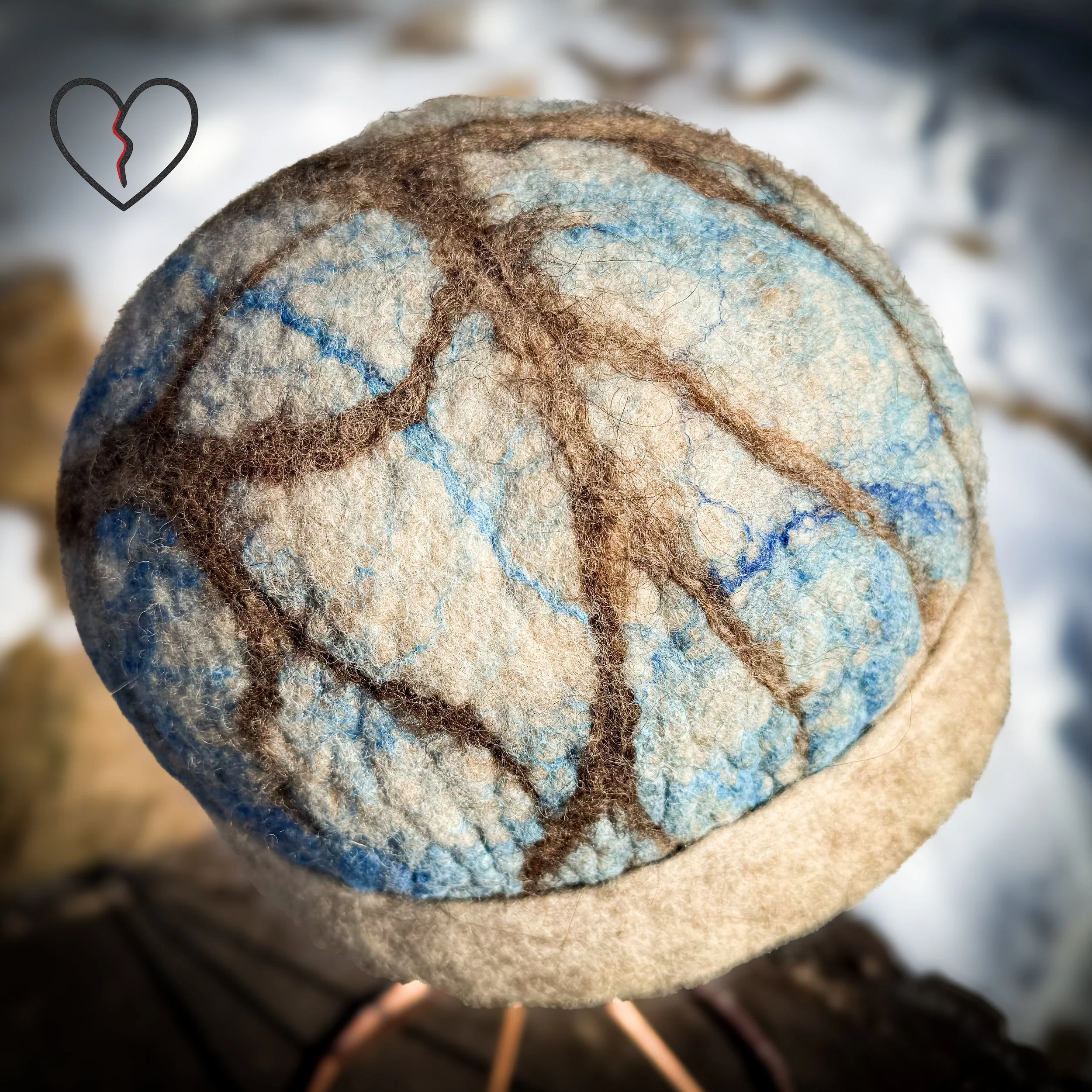 Side view of symbolic wool hat showing tree branches across blue silk sky over white felt, one of a kind fiber art hat