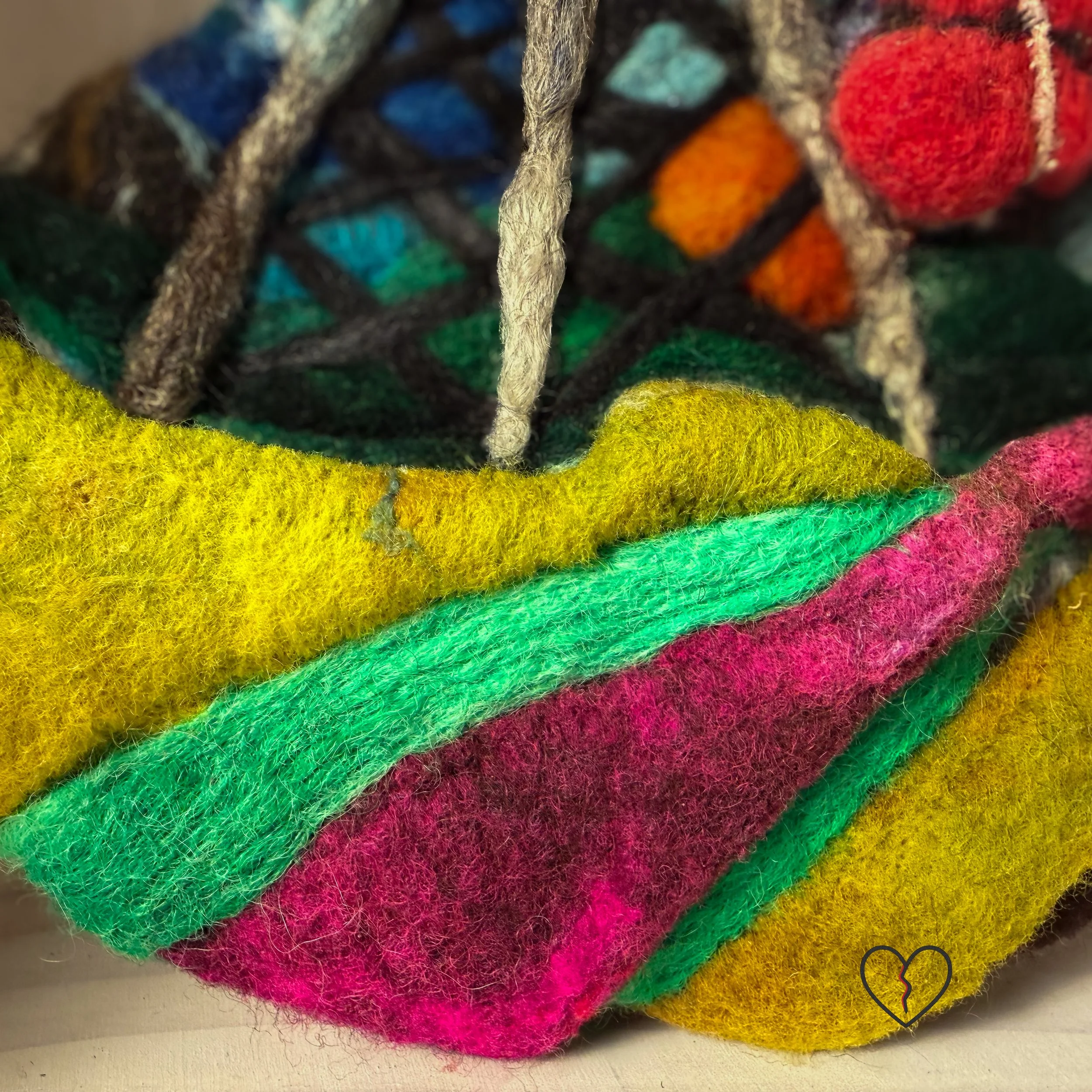 Needle felted wool wall art showing a rural landscape disrupted by a cell tower with a red broken heart hanging beneath it.