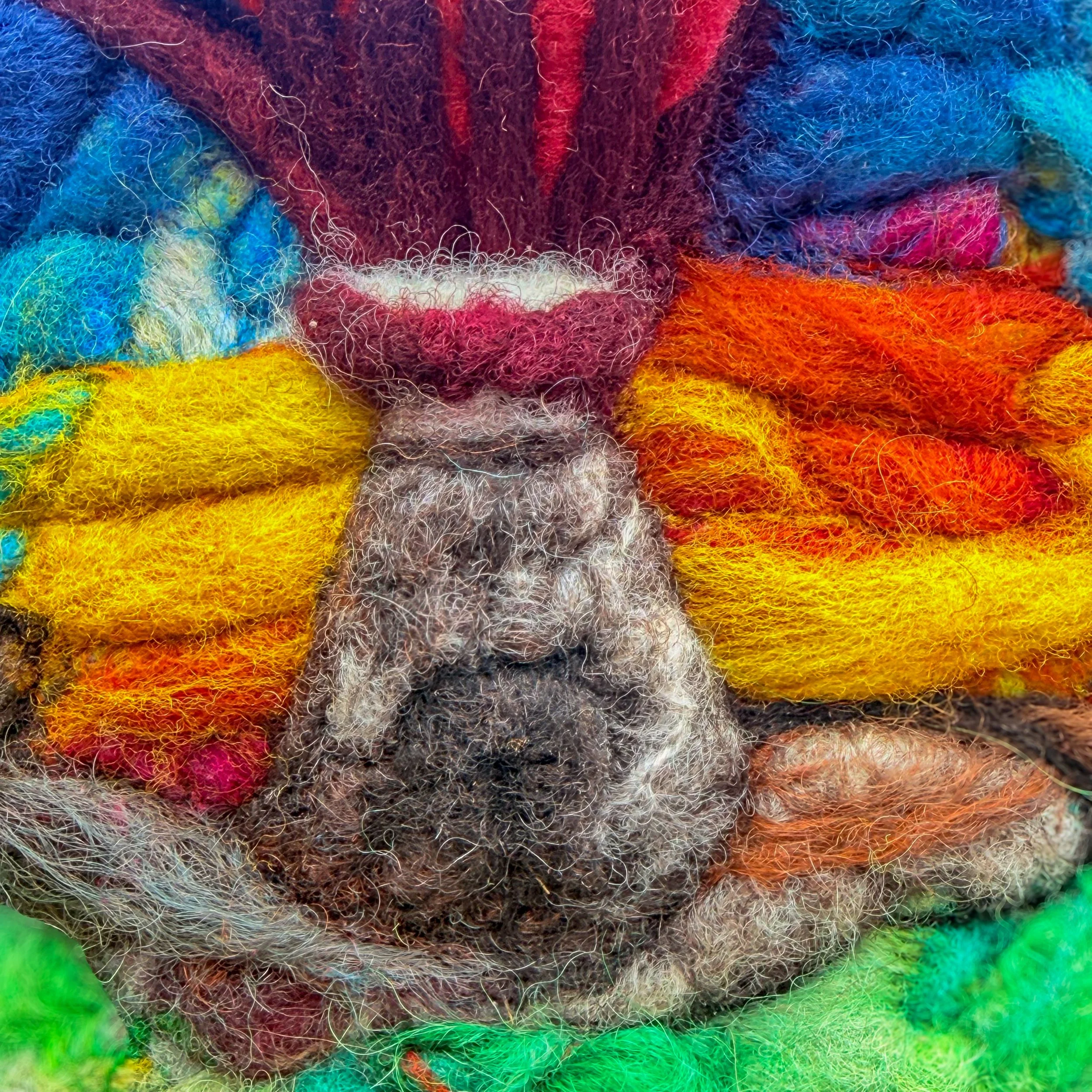 Fiber art landscape with grass foreground, stone ruin, and heart symbolizing generational trauma