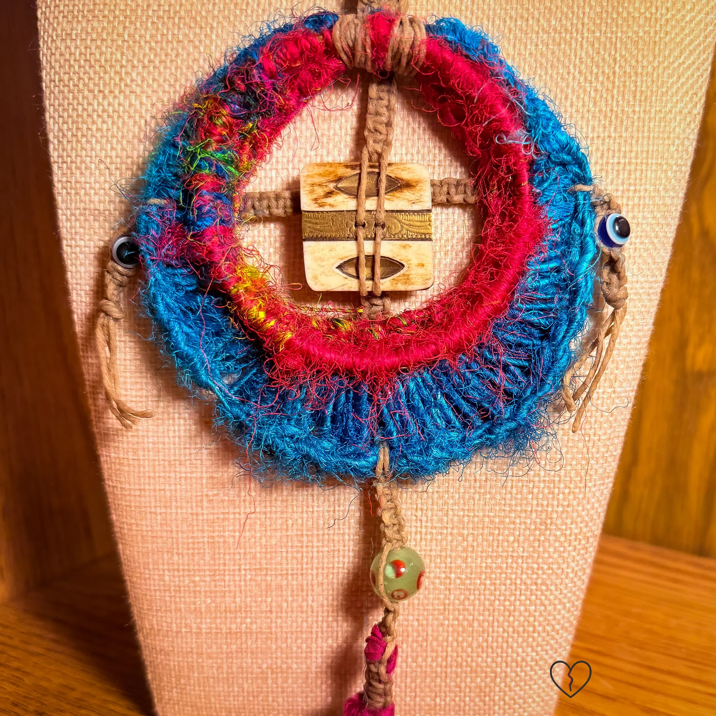 Bone button with brass inlay forming cross shape in circular fiber pendant