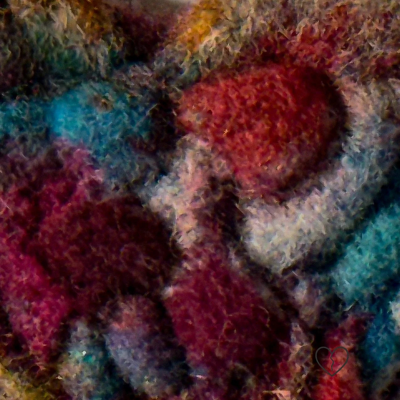 Close-up natural and hand-dyed wool fibers creating a dense, stone-like surface on a lightweight heart-shaped art pin.