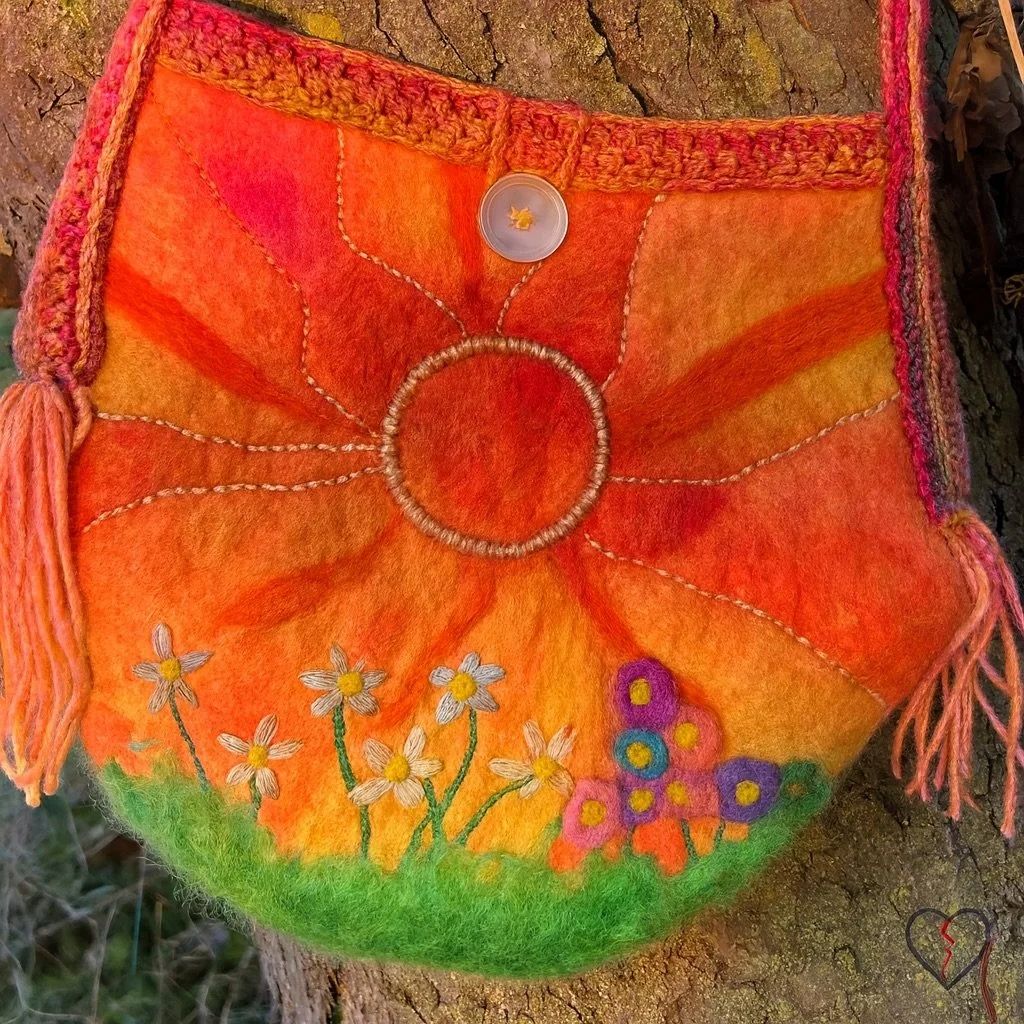 Side detail of a hand felted wool shoulder bag showing crocheted edging, hand-dyed yarn fringe, and layered fiber textures.