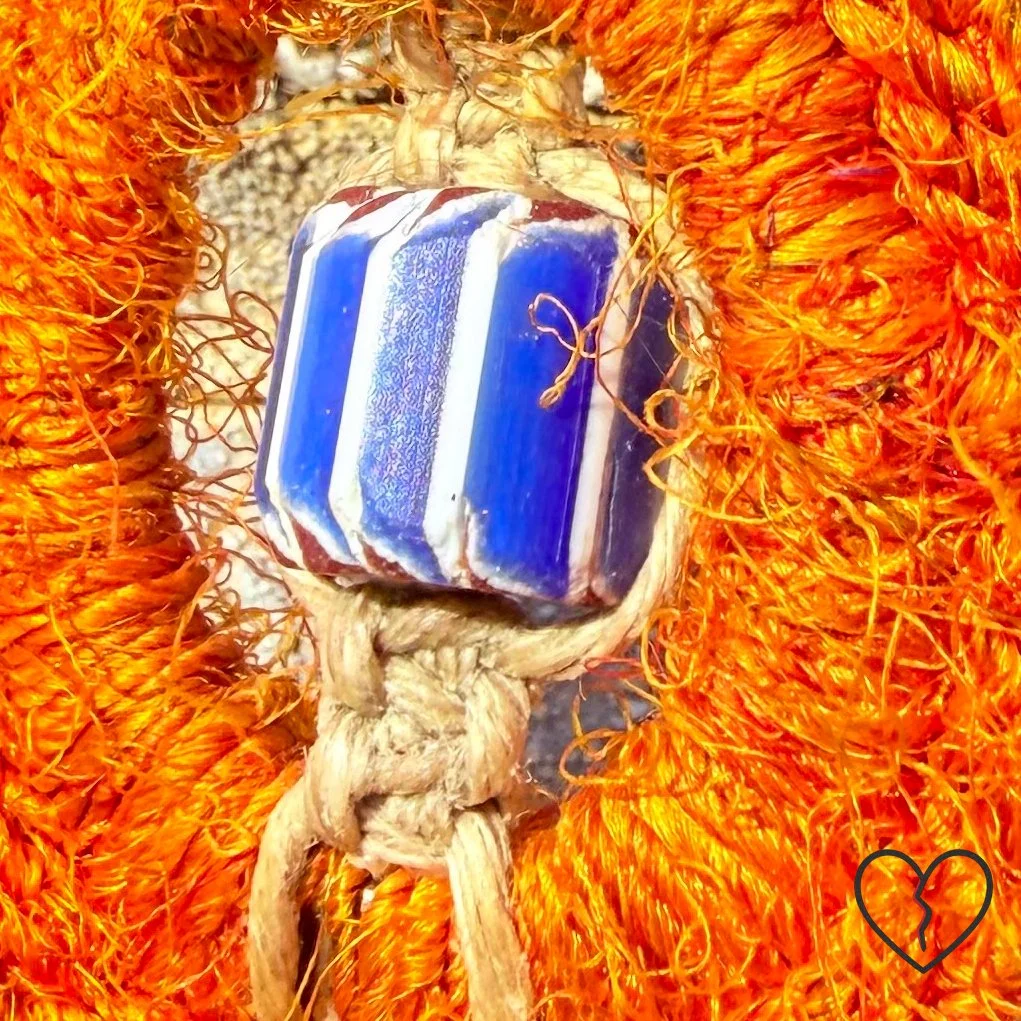 wrapped in sari silk crochet and hemp macrame with glass beads. The piece measures 11 inches long with a 2 inch largest ring and symbolizes triadic balance and transformation.