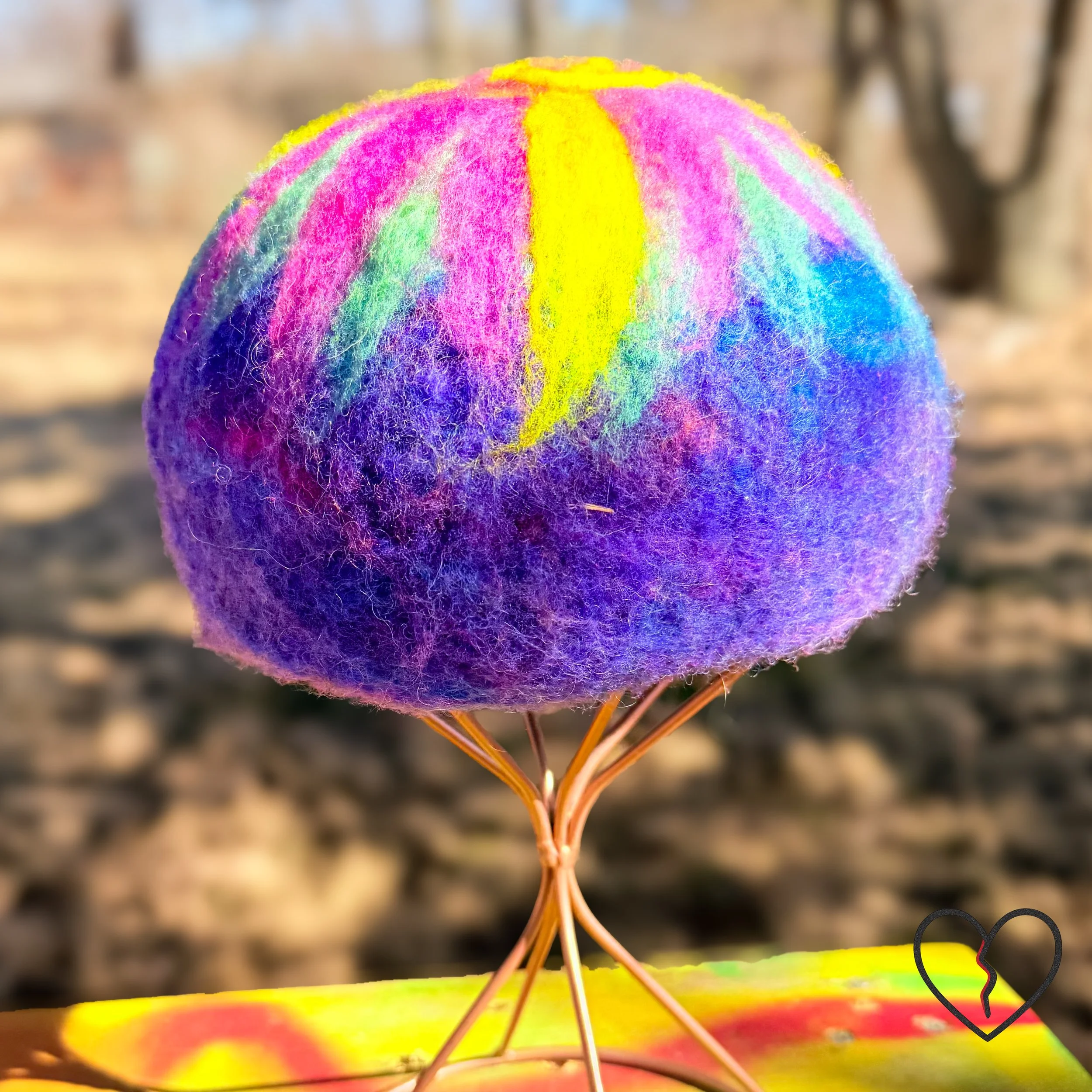 Hand dyed merino wool felted skullcap hat in purple, pink, and solar yellow with spiral sun symbol on crown