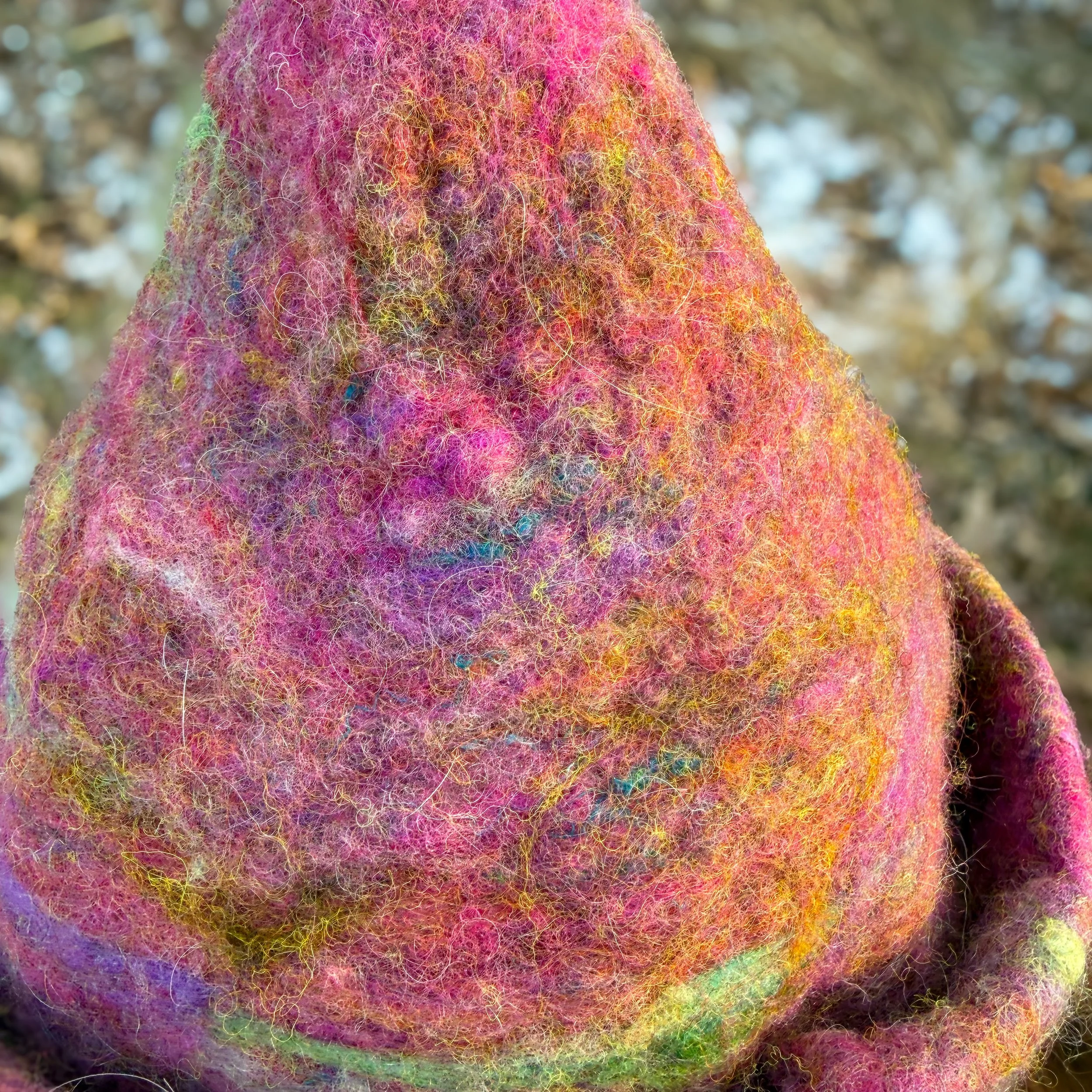 Close-up of a pink hand-felted wool witch hat showing layered fibers in merino, silk, angora, and alpaca.