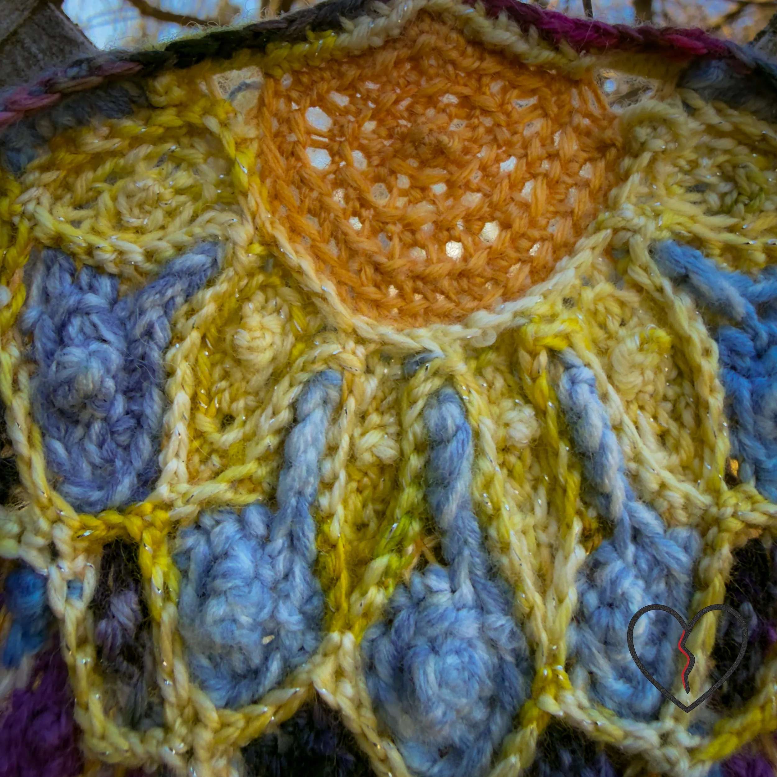 Detail of the upper section of a freeform crochet fiber artwork showing a warm sun rendered in hand-dyed wool above interlaced blue and yellow stitches.