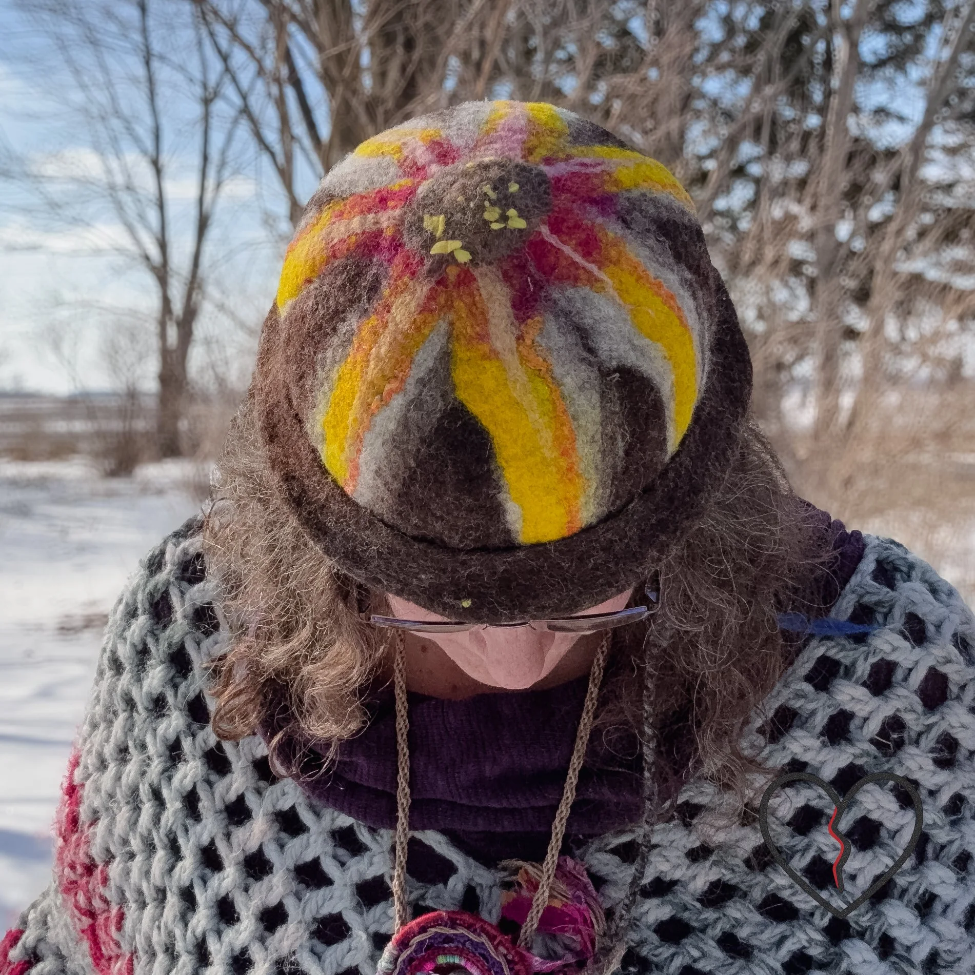 Top view of felted acorn hat with large yellow flower centered on crown and layered wool texture.