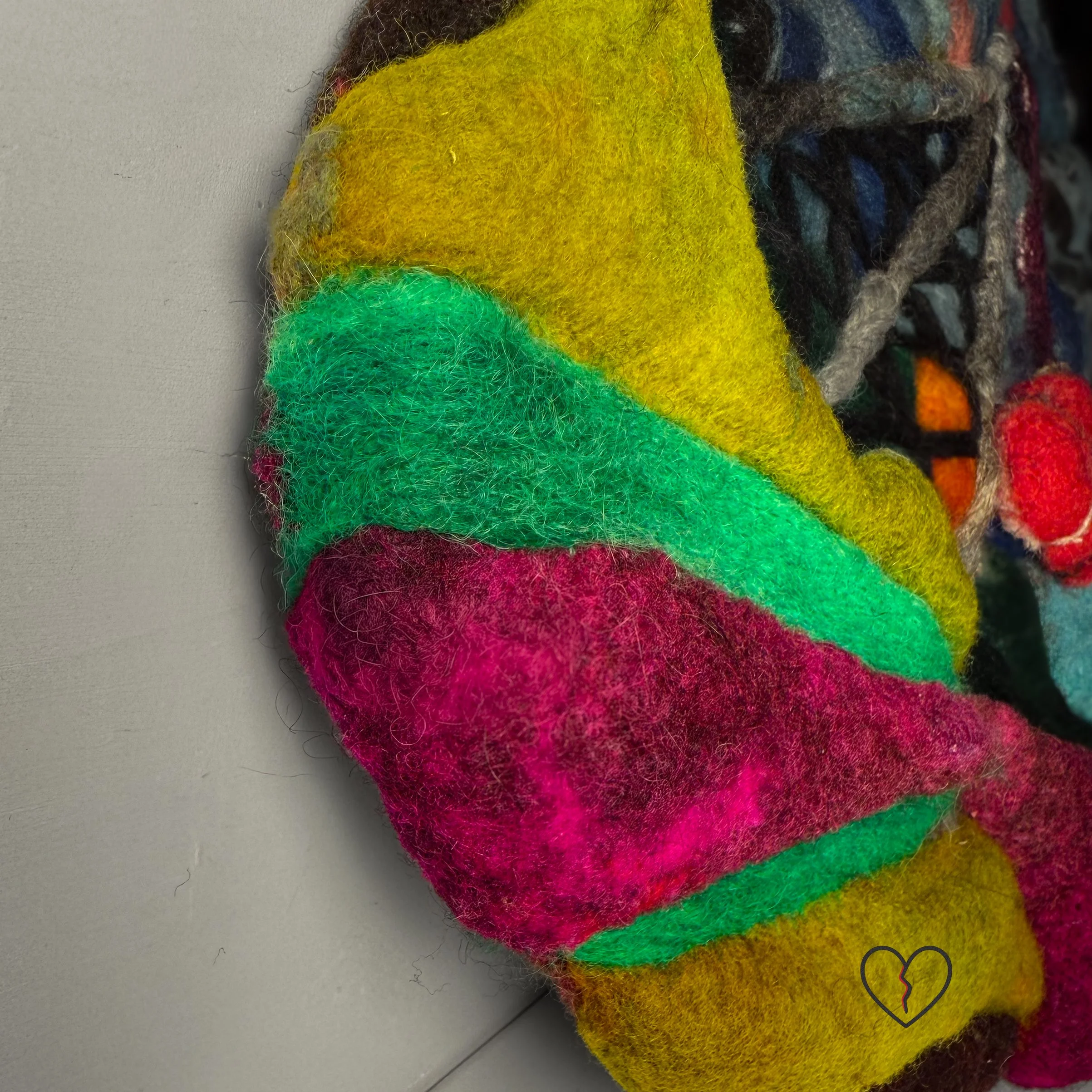 Needle felted wool wall art showing a rural landscape disrupted by a cell tower with a red broken heart hanging beneath it.