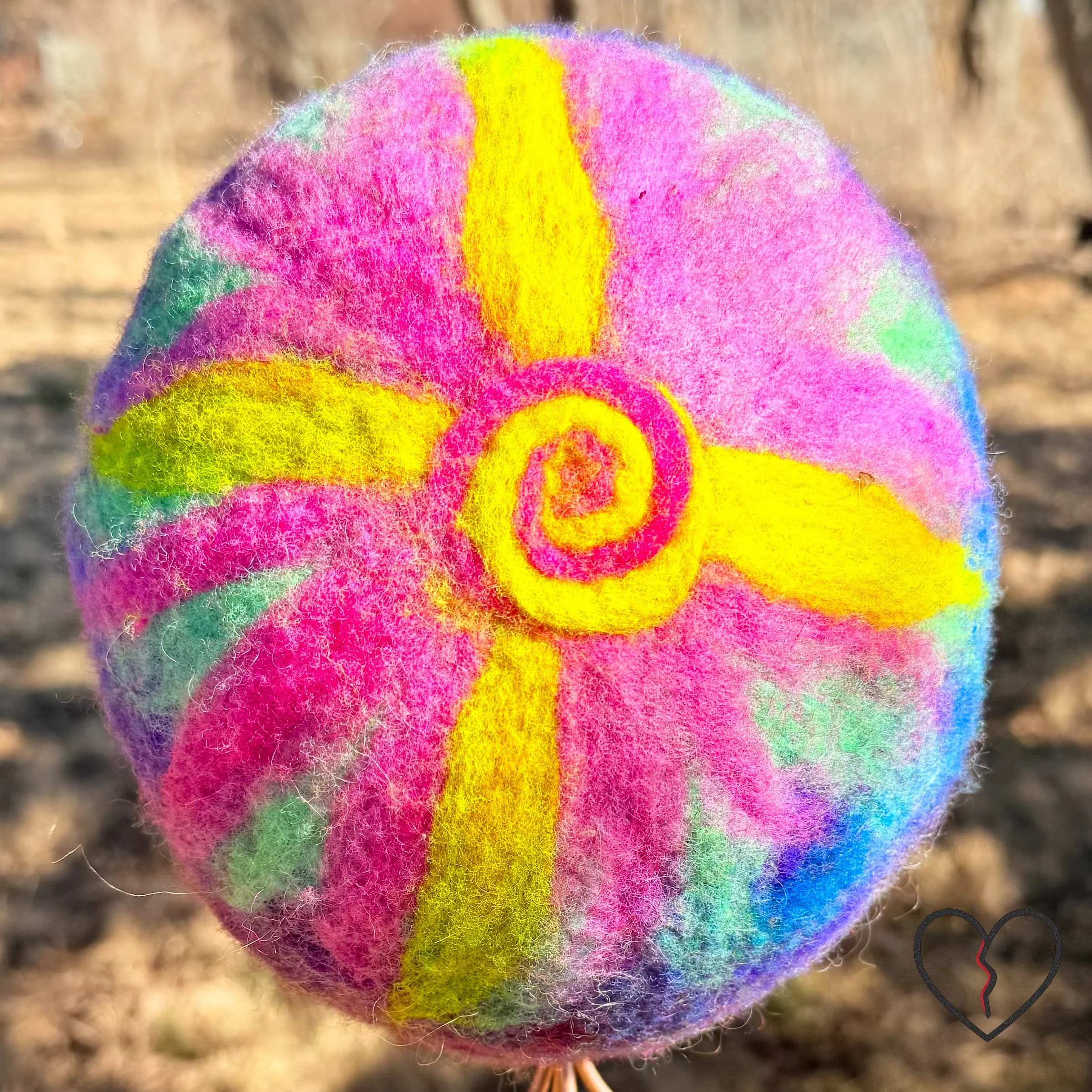 Hand dyed merino wool felted skullcap hat in purple, pink, and solar yellow with spiral sun symbol on crown