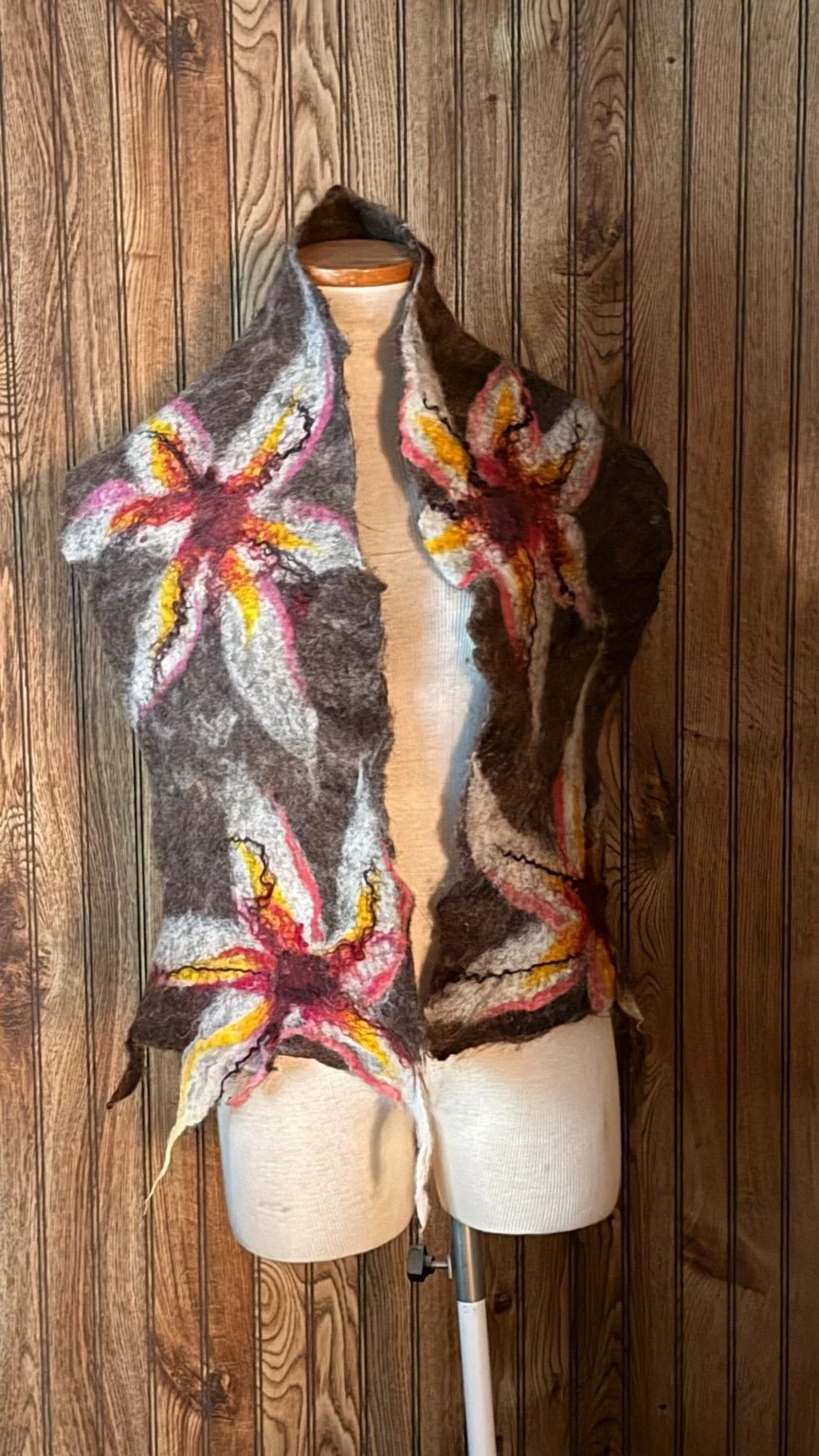 Hand-felted wool flower scarf displayed on dress form against wood backdrop