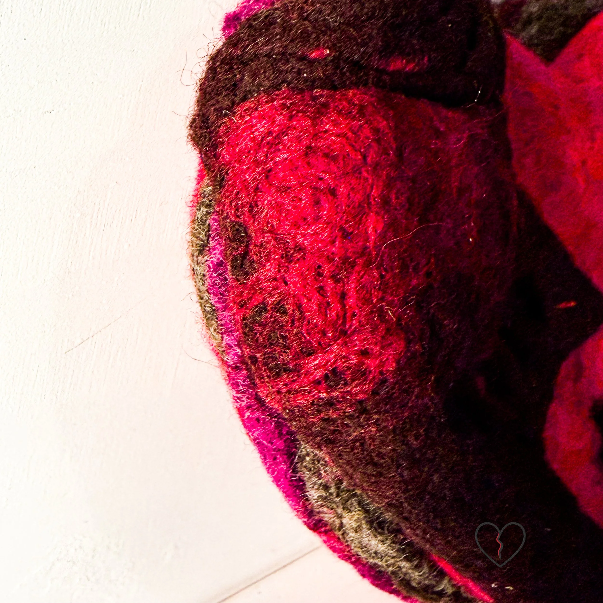 Side view of needle-felted wool wall art with exposed layered dyed wool fibers, showing sculptural depth and construction