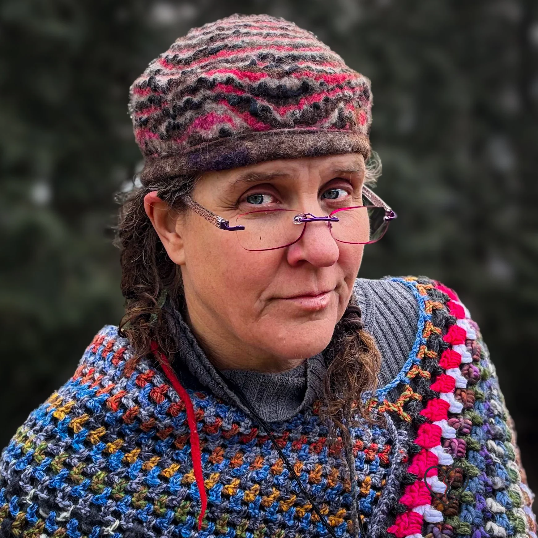 Hand-felted wool hat worn above the ear, featuring rippling stripes in natural brown, white, and hand-dyed pink merino, with a folded brim and sculptural crown.