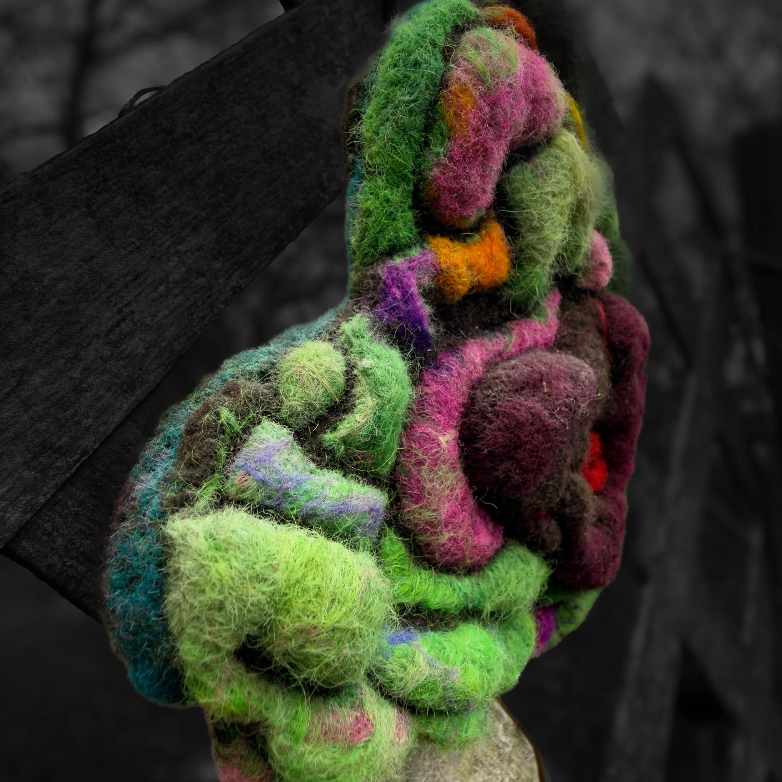 Side view of textured felt heart sculpture showing layered green and purple wool forms