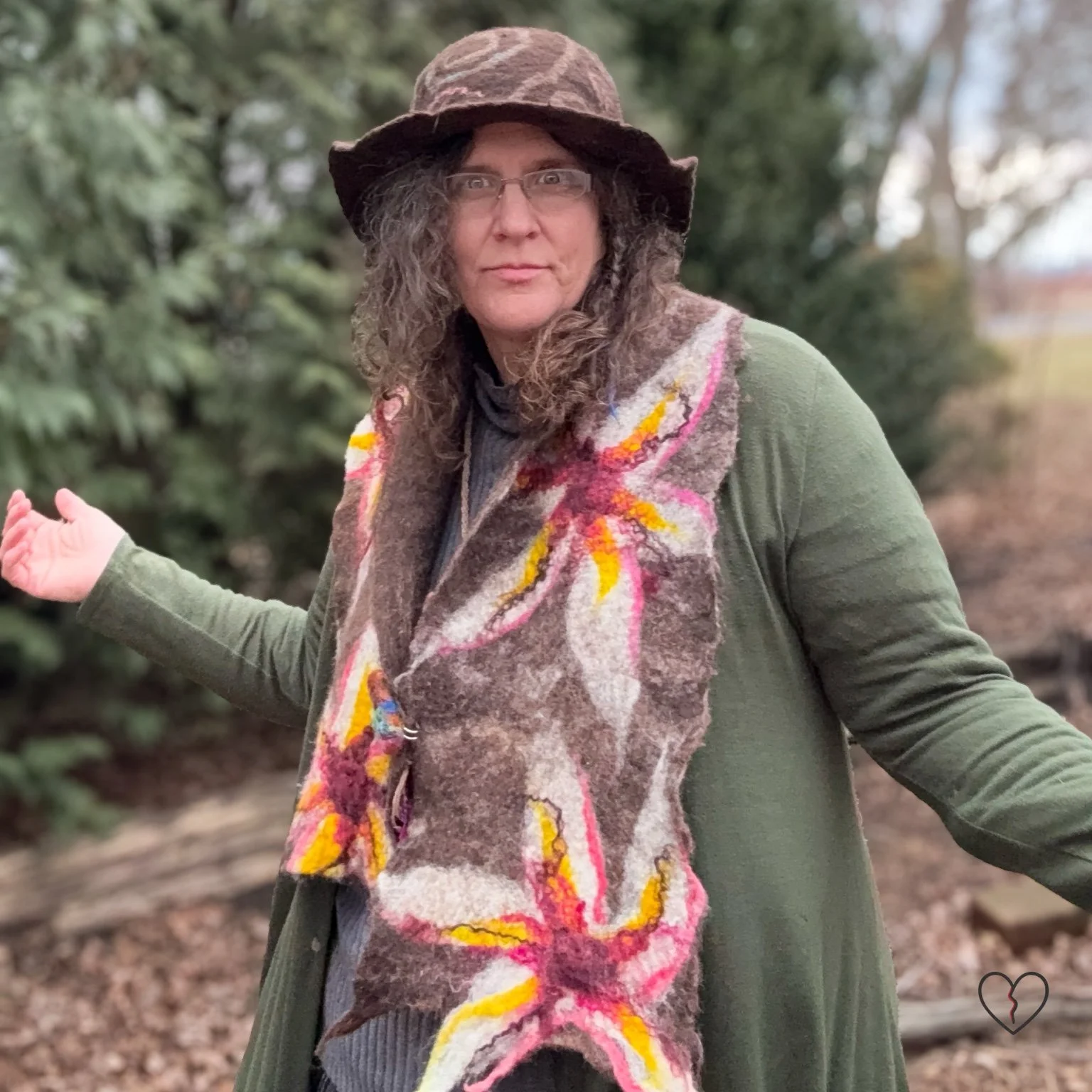 Model wearing a long hand-felted scarf with white, pink, and gold floral designs